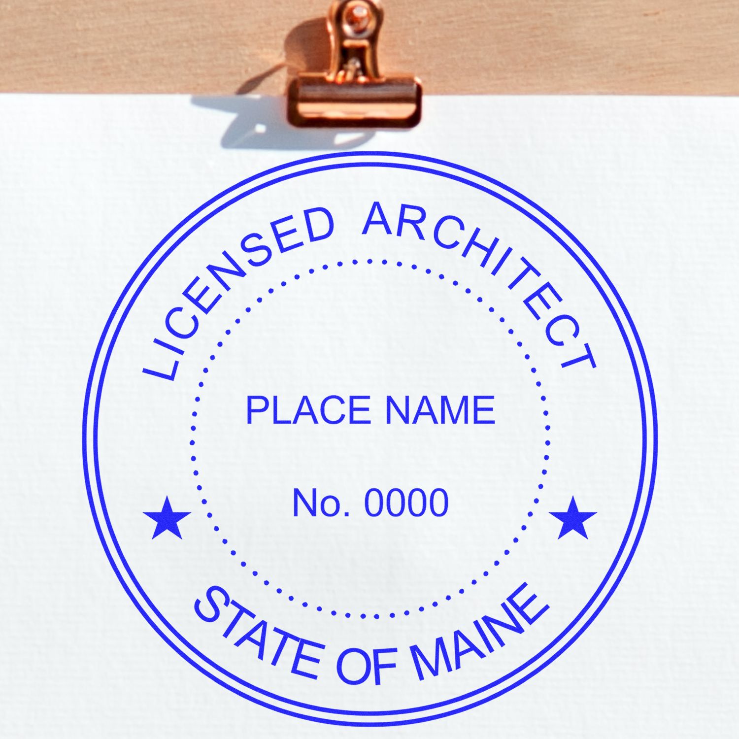 Self Inking Maine Architect Stamp with blue ink on white paper, displaying Licensed Architect, State of Maine, Place Name, No. 0000 .