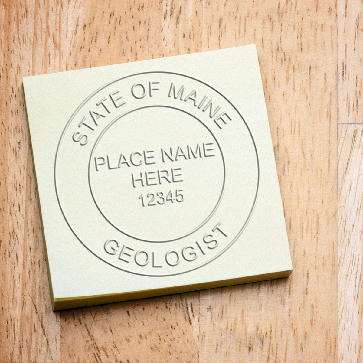 A lifestyle photo showing a stamped image of the Heavy Duty Cast Iron Maine Geologist Seal Embosser on a piece of paper