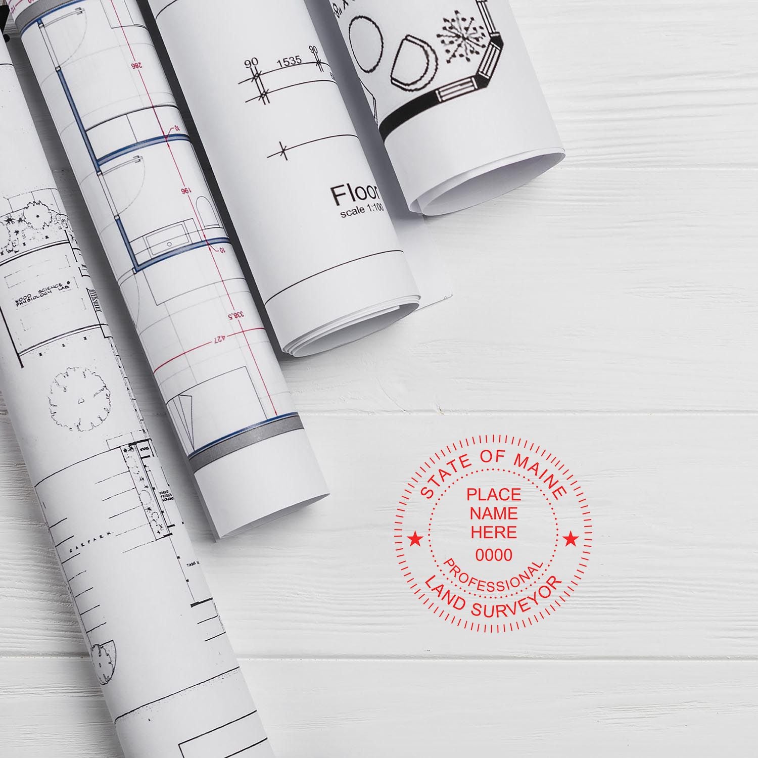 Self Inking Maine Land Surveyor Stamp imprint on white paper with rolled architectural blueprints in the background.