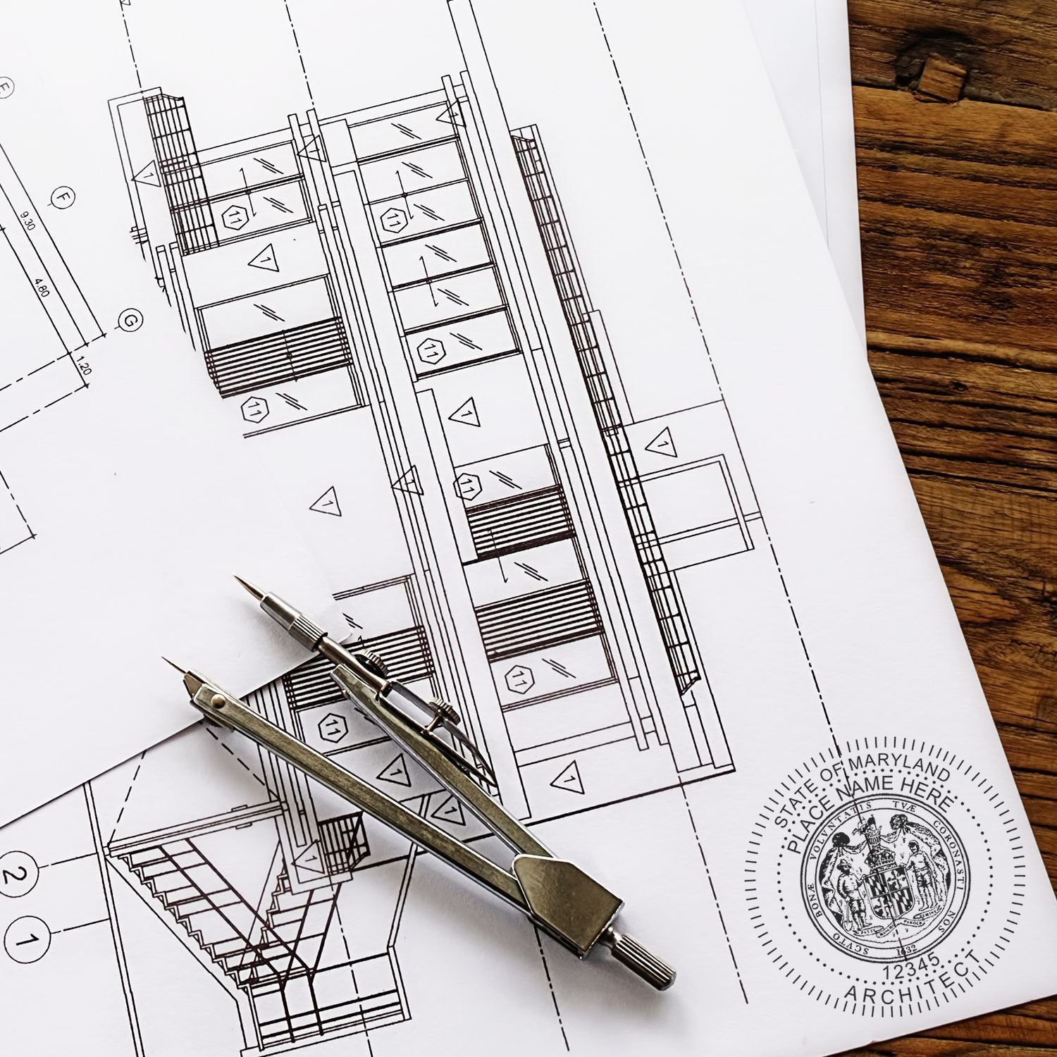 Maryland Architect Seal Stamp on architectural blueprints with a metal compass placed on top.