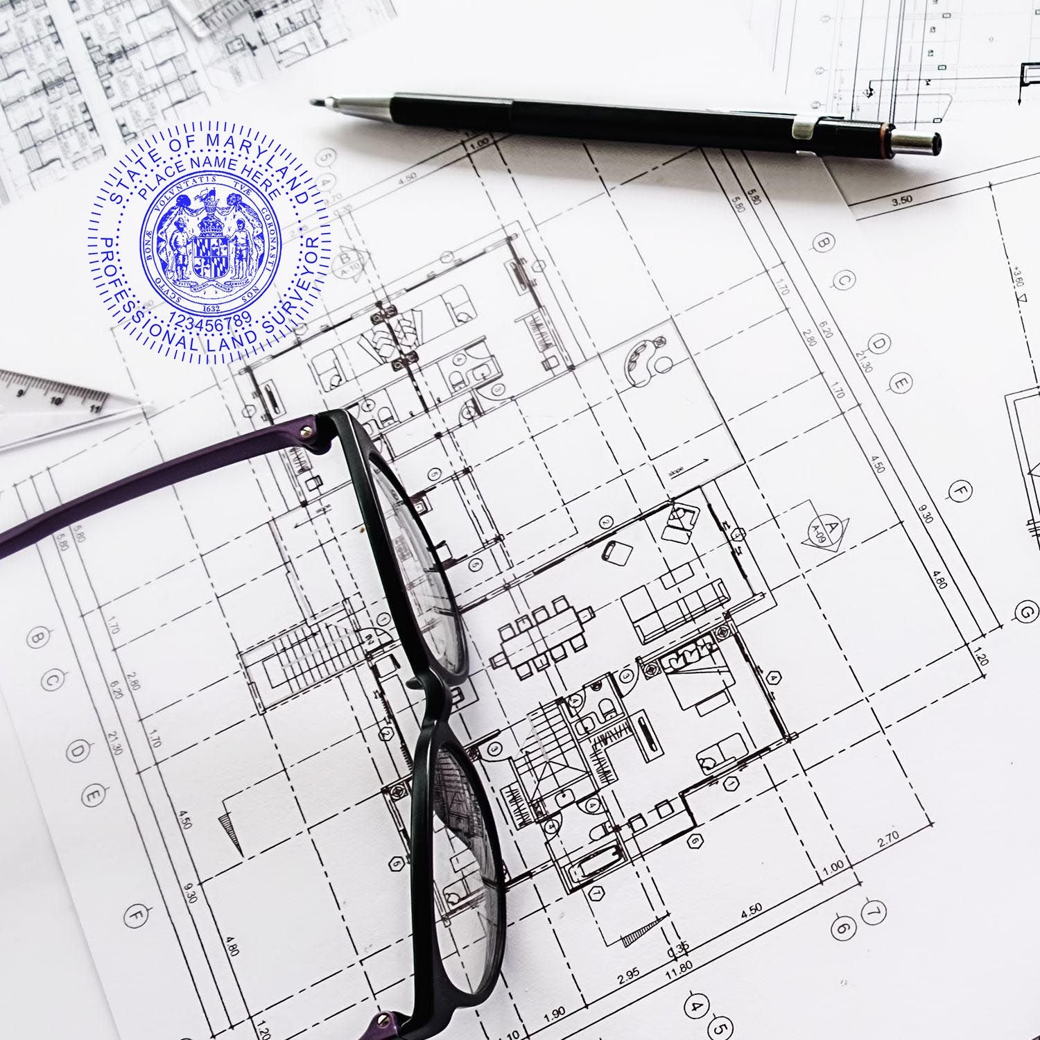 Self Inking Maryland Land Surveyor Stamp on architectural blueprints with glasses and a pen nearby.