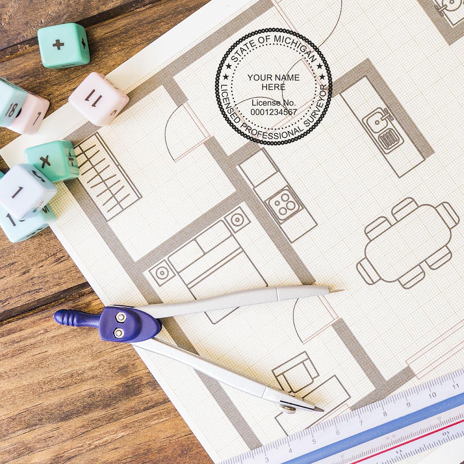 Self Inking Michigan Land Surveyor Stamp on architectural blueprint with drafting tools and dice on a wooden table.