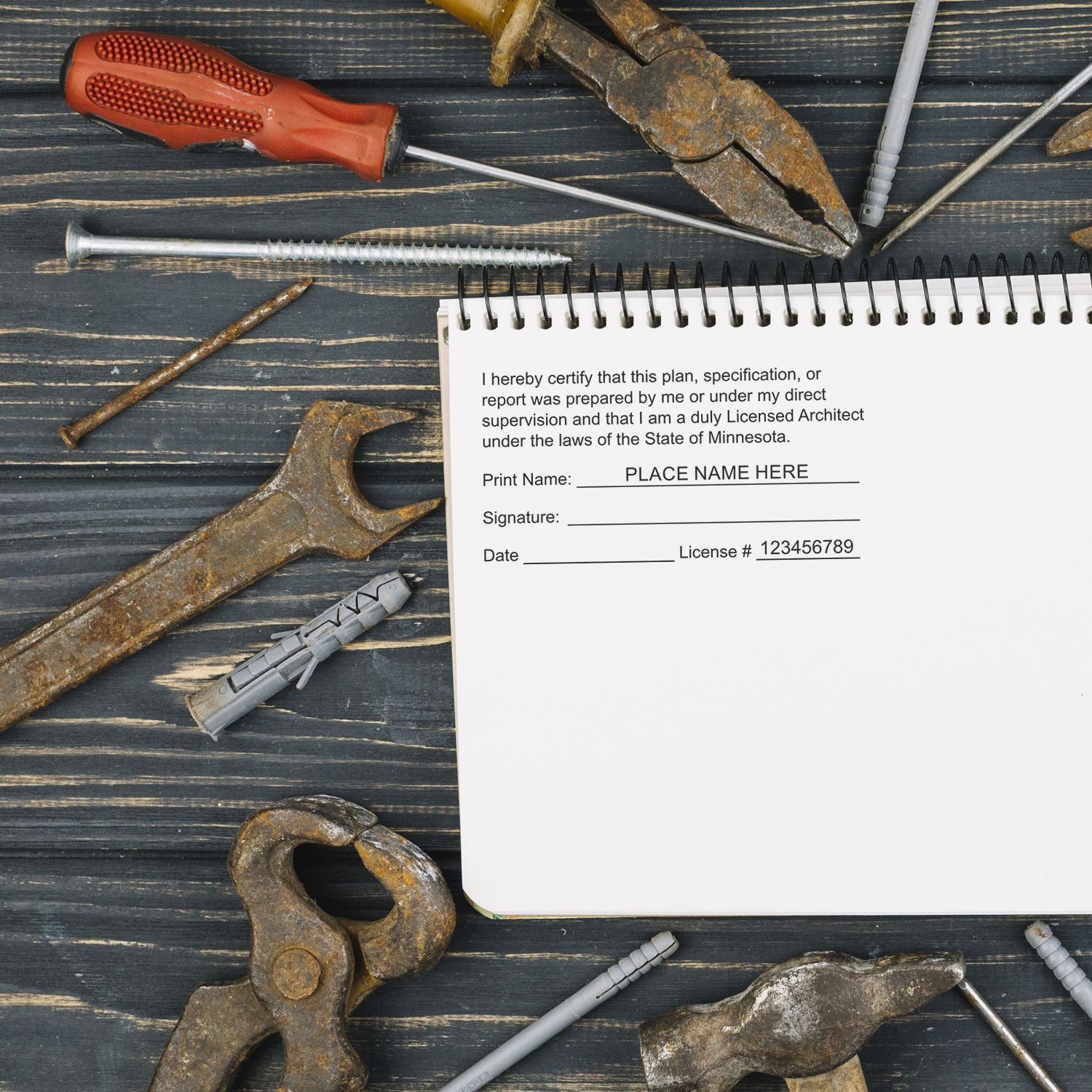 Self Inking Minnesota Architect Stamp in use on a document surrounded by various tools on a wooden surface.