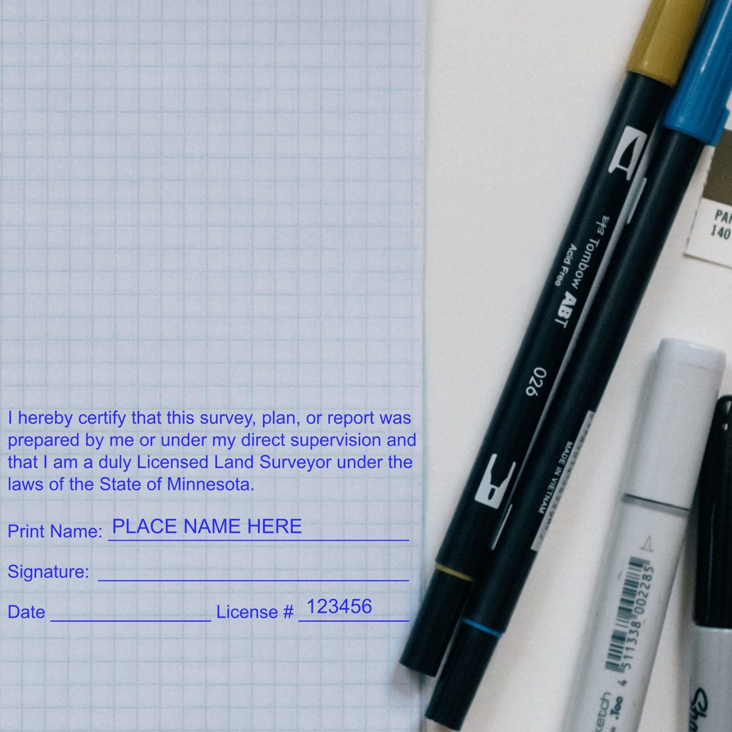 Self Inking Minnesota Land Surveyor Stamp on a graph paper with pens and markers nearby.