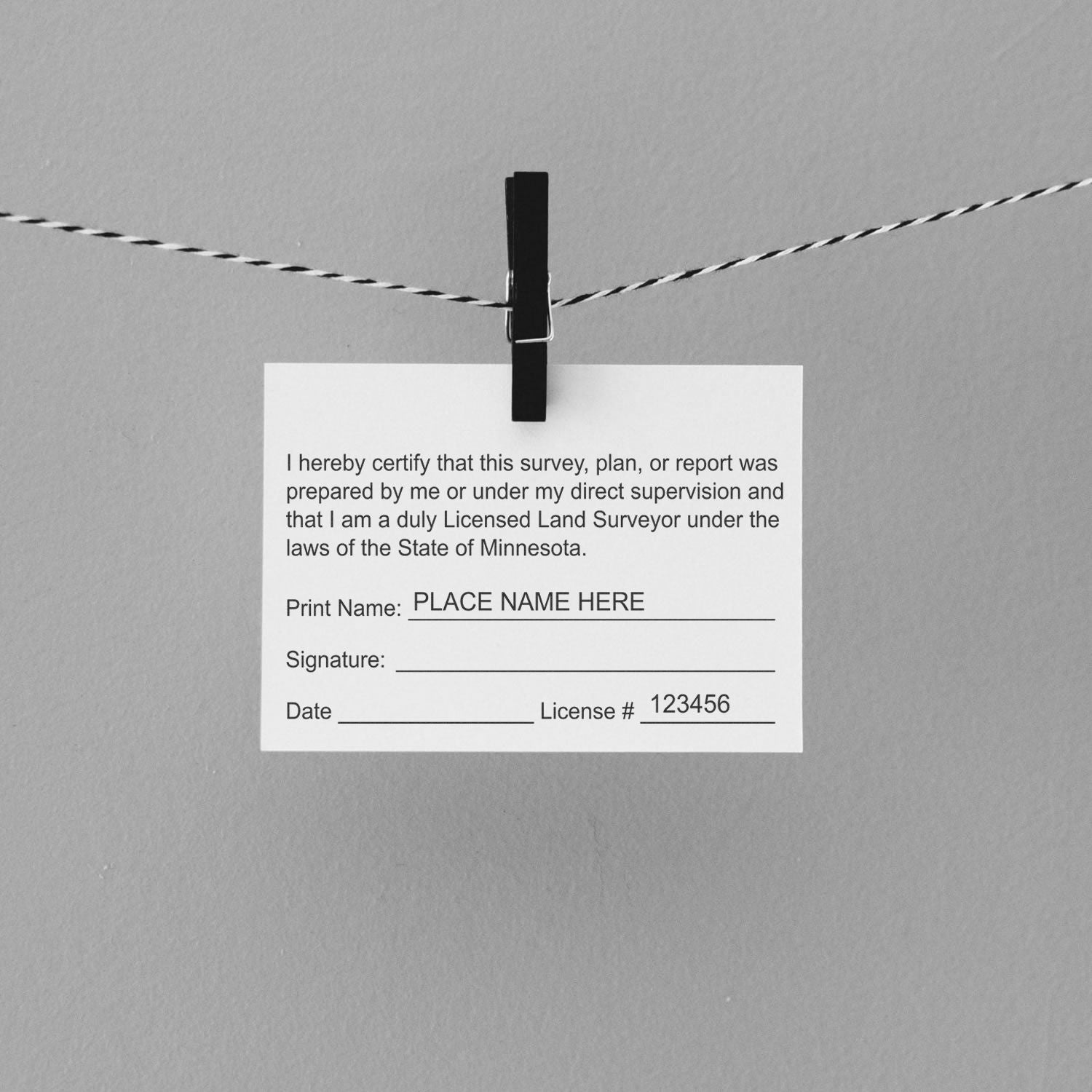 Self Inking Minnesota Land Surveyor Stamp used on a certification card, clipped to a string with a black clothespin.