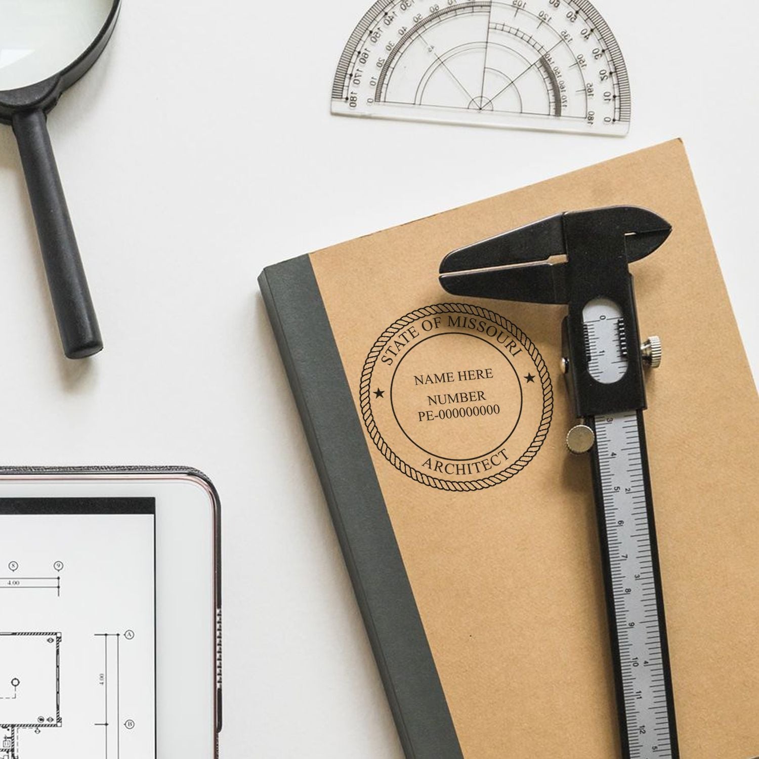 Missouri Architect Seal Stamp on a notebook with a caliper, protractor, magnifying glass, and tablet displaying architectural plans.