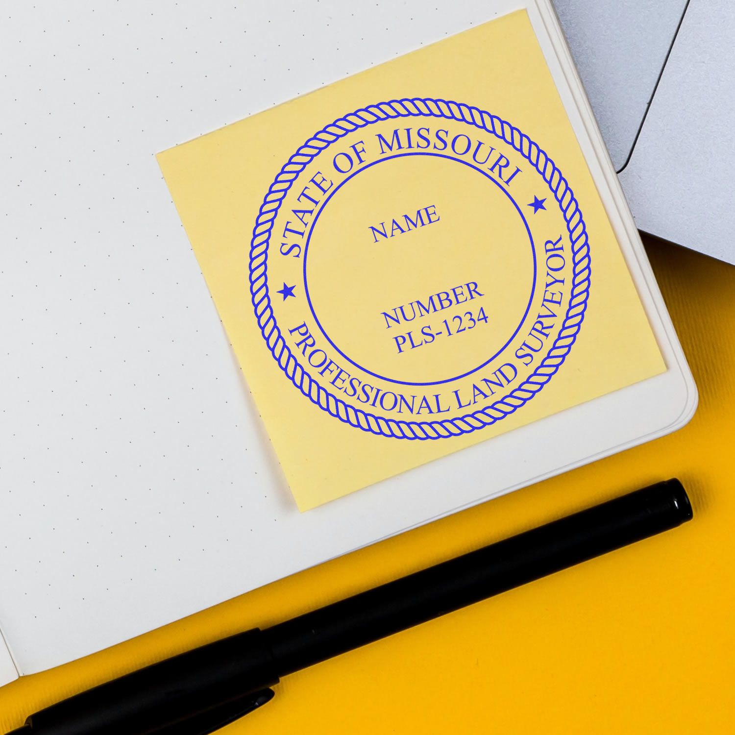 Digital Missouri Land Surveyor Stamp, Electronic Seal for Missouri Land Surveyor, on a yellow sticky note next to a black pen and notebook.