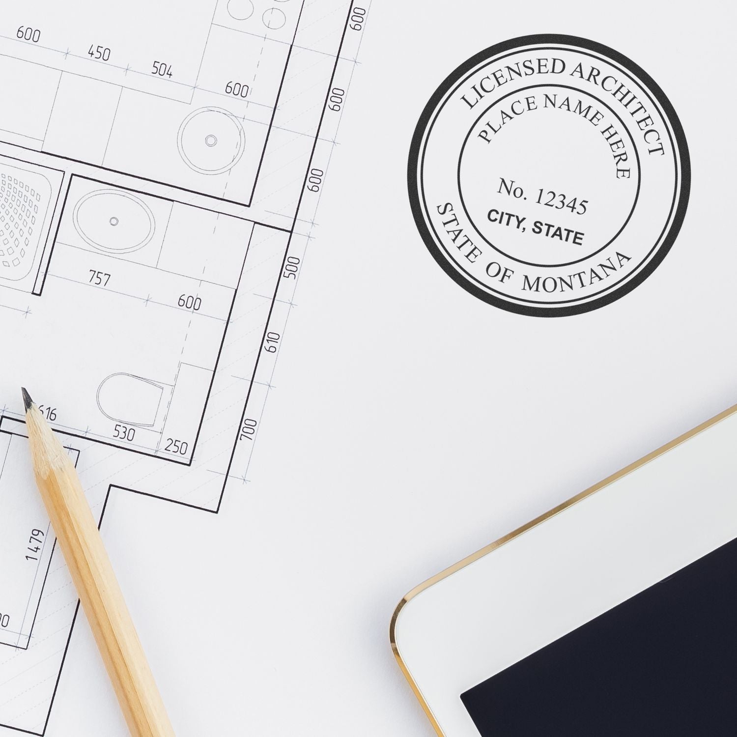 Premium MaxLight Pre-Inked Montana Architectural Stamp used on architectural plans, with a pencil and tablet nearby.