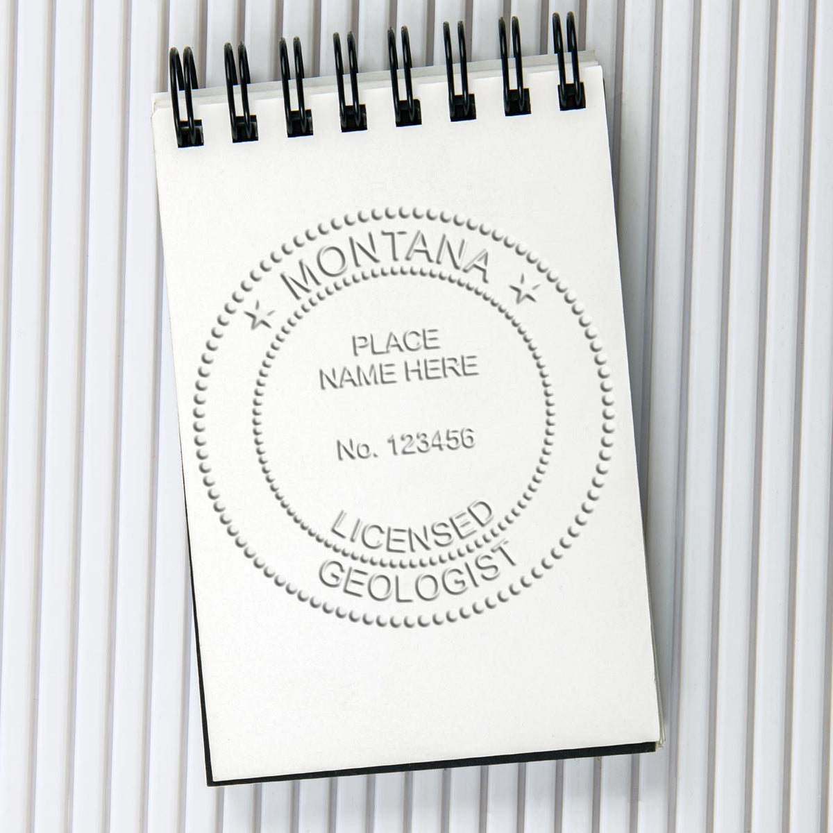 An in use photo of the Hybrid Montana Geologist Seal showing a sample imprint on a cardstock