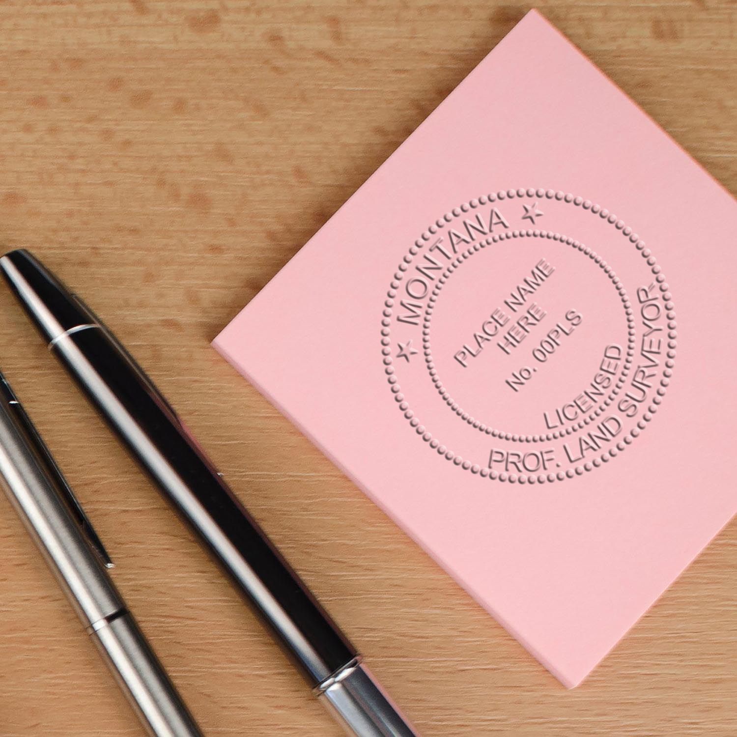 An in use photo of the Gift Montana Land Surveyor Seal showing a sample imprint on a cardstock