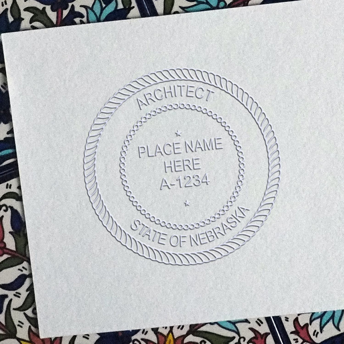 An in use photo of the Hybrid Nebraska Architect Seal showing a sample imprint on a cardstock