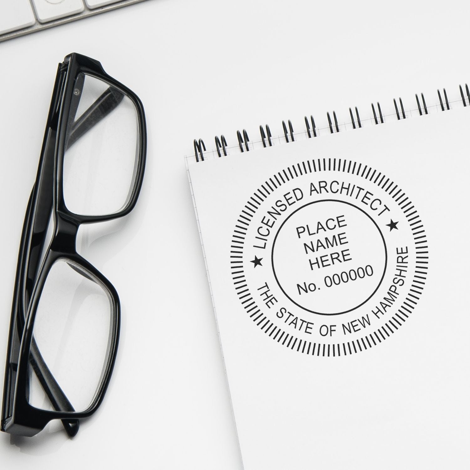 New Hampshire Architect Seal Stamp on a white notepad next to black-framed glasses and a keyboard.