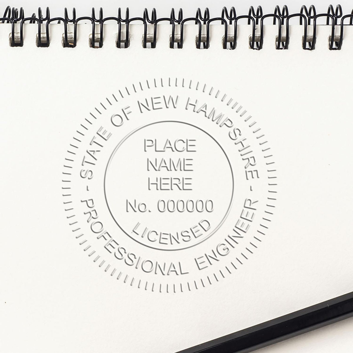 An alternative view of the Heavy Duty Cast Iron New Hampshire Engineer Seal Embosser stamped on a sheet of paper showing the image in use