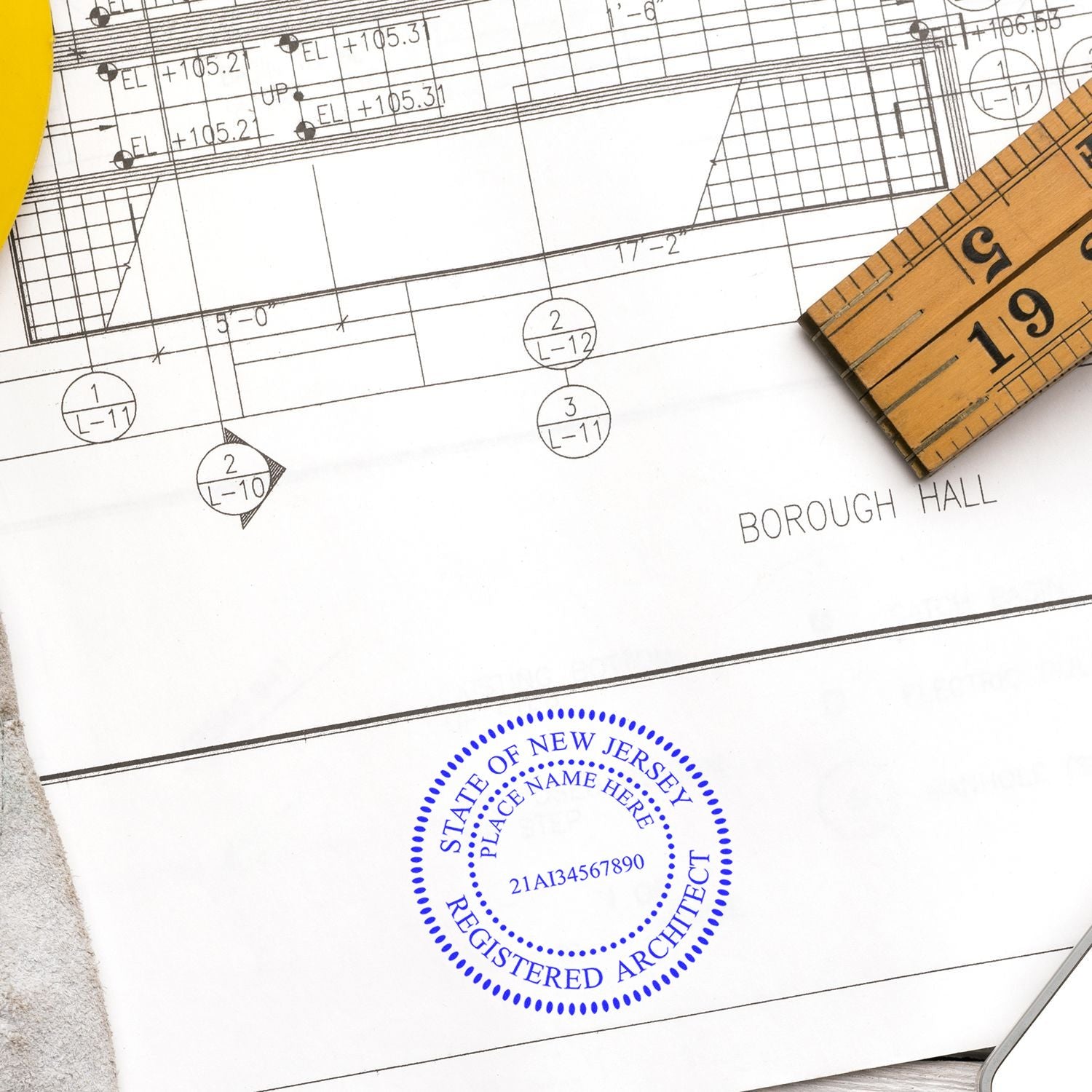 Self Inking New Jersey Architect Stamp in blue ink on architectural plans with a ruler and yellow tool in the background.