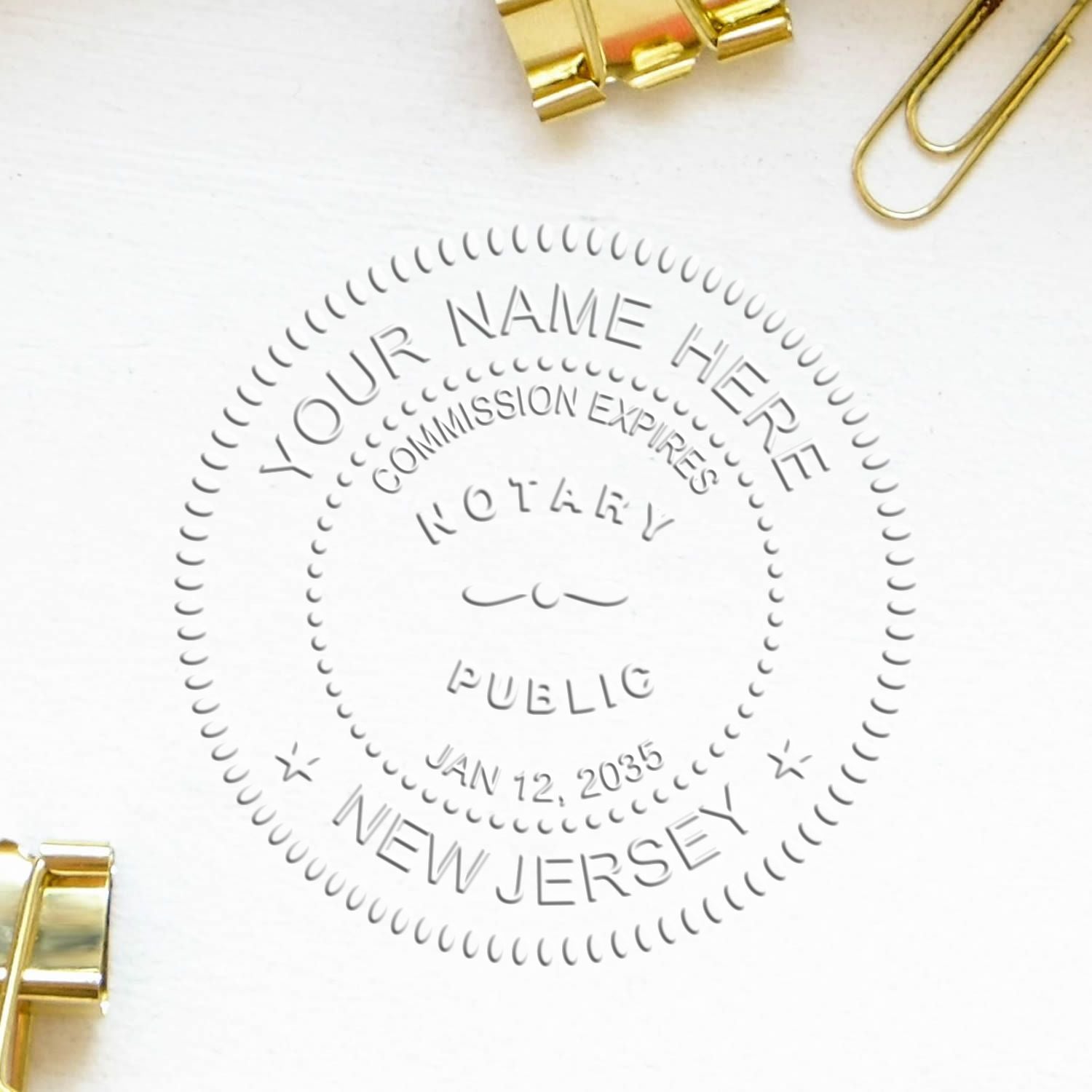 New Jersey Handheld Notary Seal Embosser imprint on white paper, surrounded by gold binder clips and a paperclip.