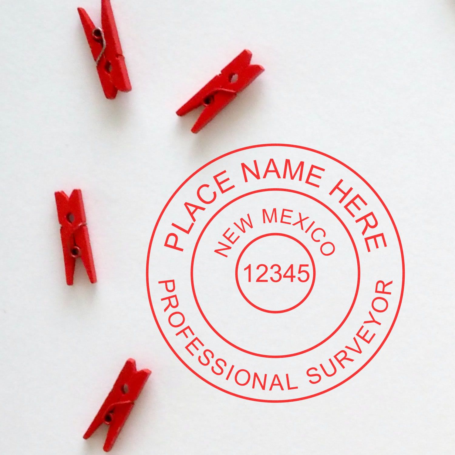 Premium MaxLight Pre-Inked New Mexico Surveyors Stamp with red text and four red clothespins on a white background.