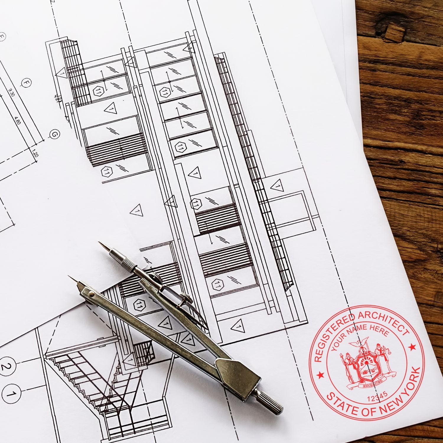 Blueprints with a New York Architect Seal Stamp, a compass, and a pencil on a wooden table.