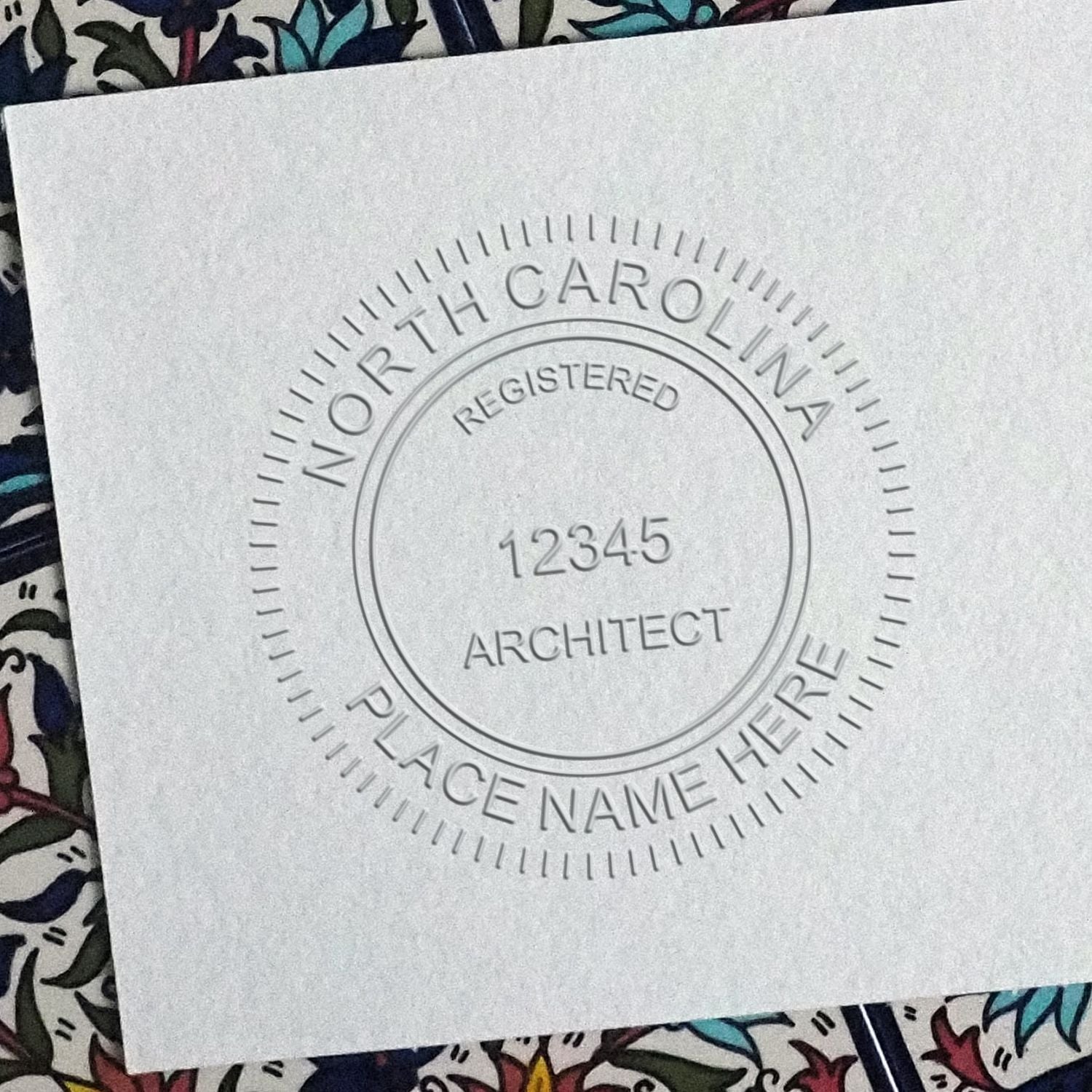 A lifestyle photo showing a stamped image of the Handheld North Carolina Architect Seal Embosser on a piece of paper
