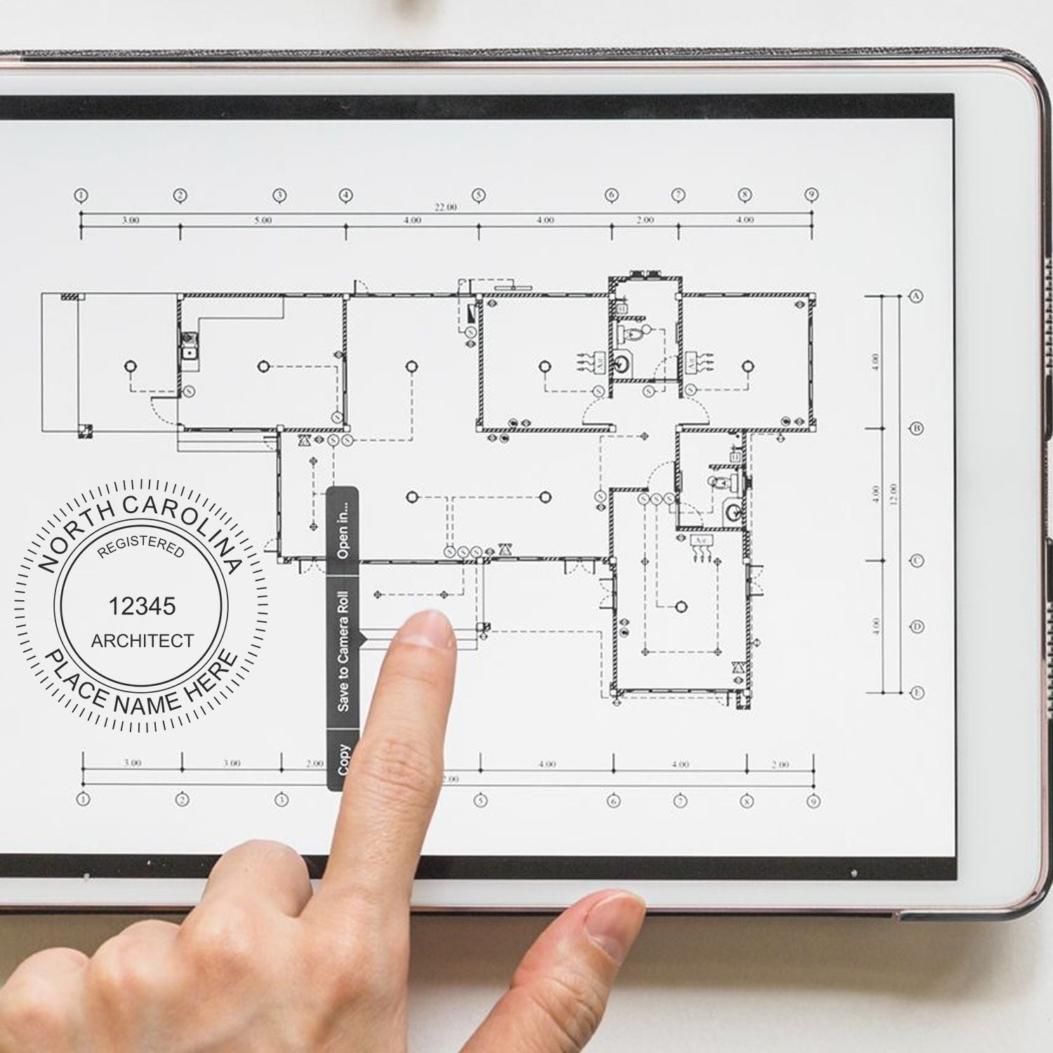 Finger pointing at a tablet displaying architectural plans with a North Carolina Architect Seal Stamp visible on the screen.