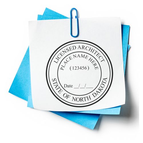 North Dakota Architect Seal Stamp on white paper with blue sheets underneath, secured by a blue paperclip.