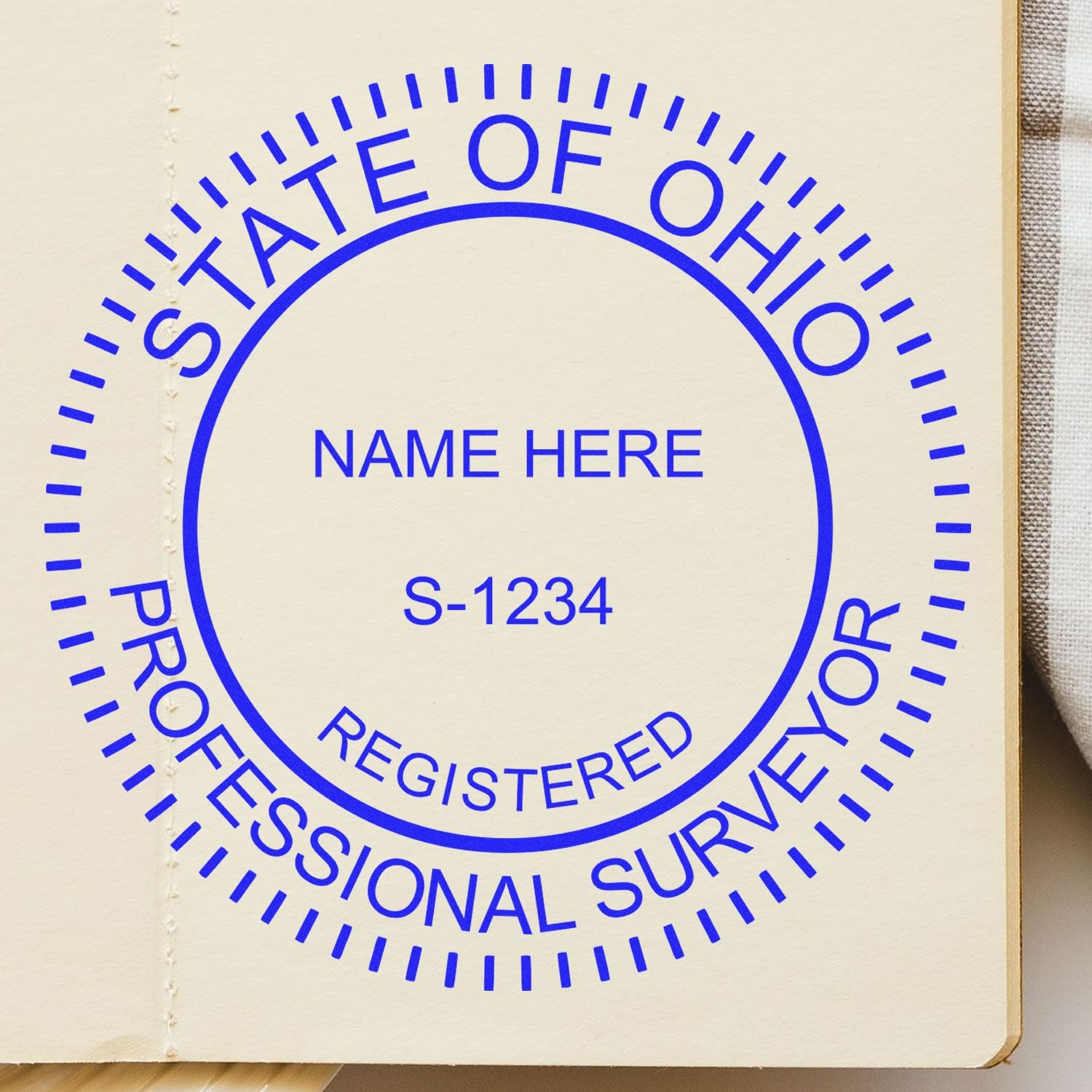 Premium MaxLight Pre-Inked Ohio Surveyors Stamp imprint on a beige surface, displaying STATE OF OHIO PROFESSIONAL SURVEYOR in blue text.