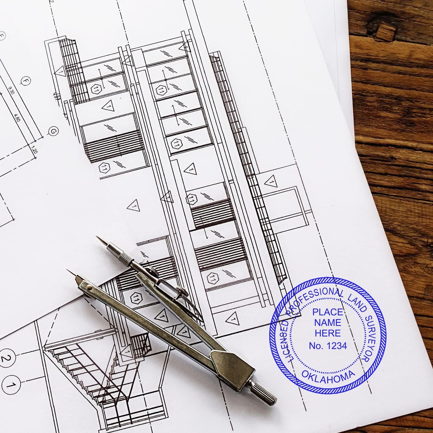 Blueprint with a Premium MaxLight Pre-Inked Oklahoma Surveyors Stamp, compass, and pencil on a wooden table.