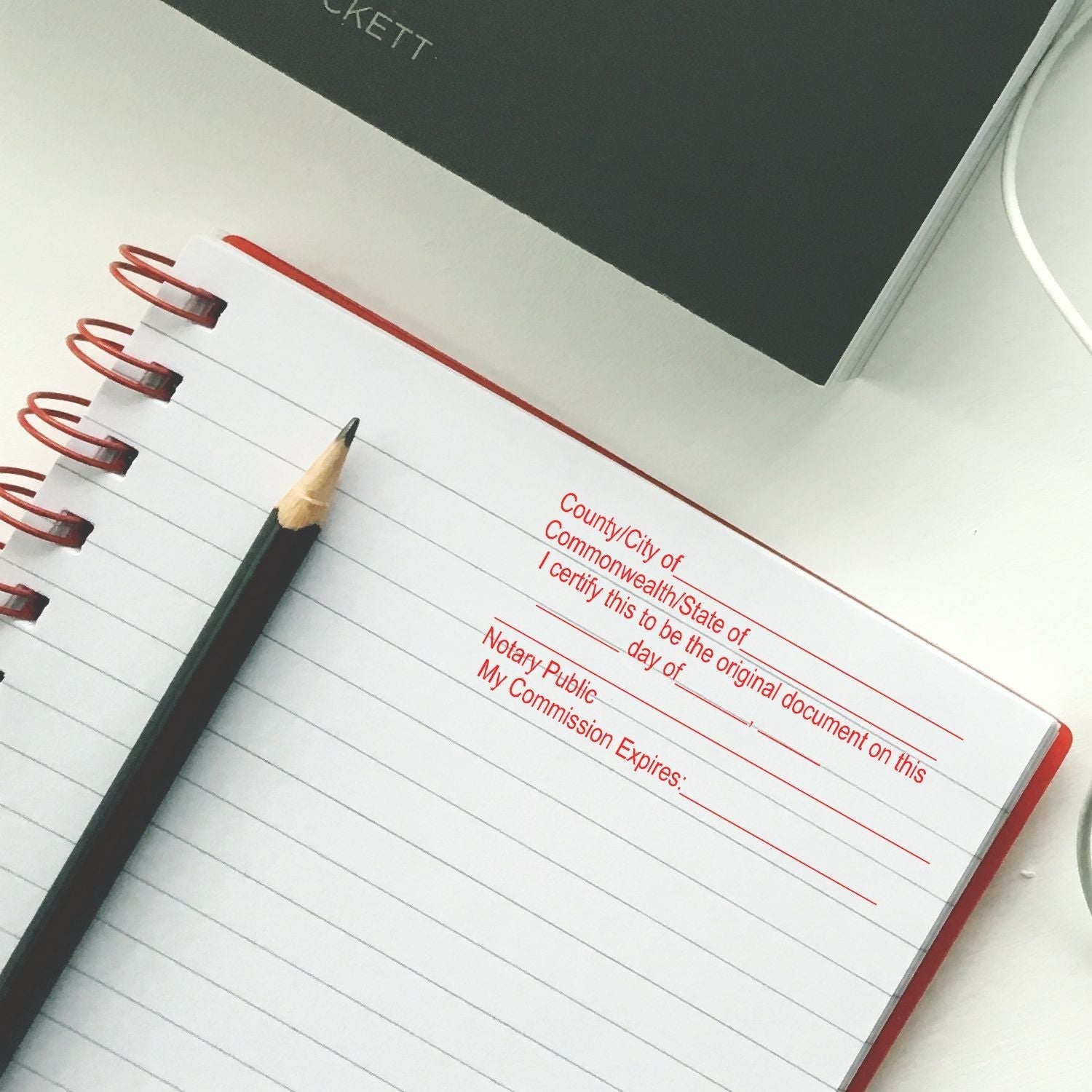 A Regular Notary Original Document Stamp imprint on a lined notebook page with a pencil beside it, ready for notary use.