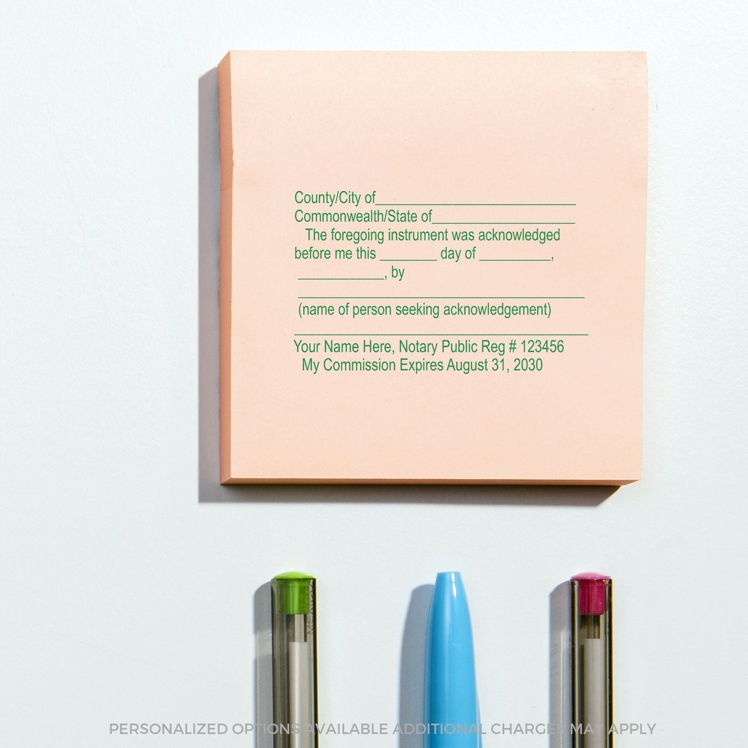 Slim Pre-Inked Notary Acknowledgment Stamp in use on a pink notepad, with green and red pens and a blue highlighter nearby.