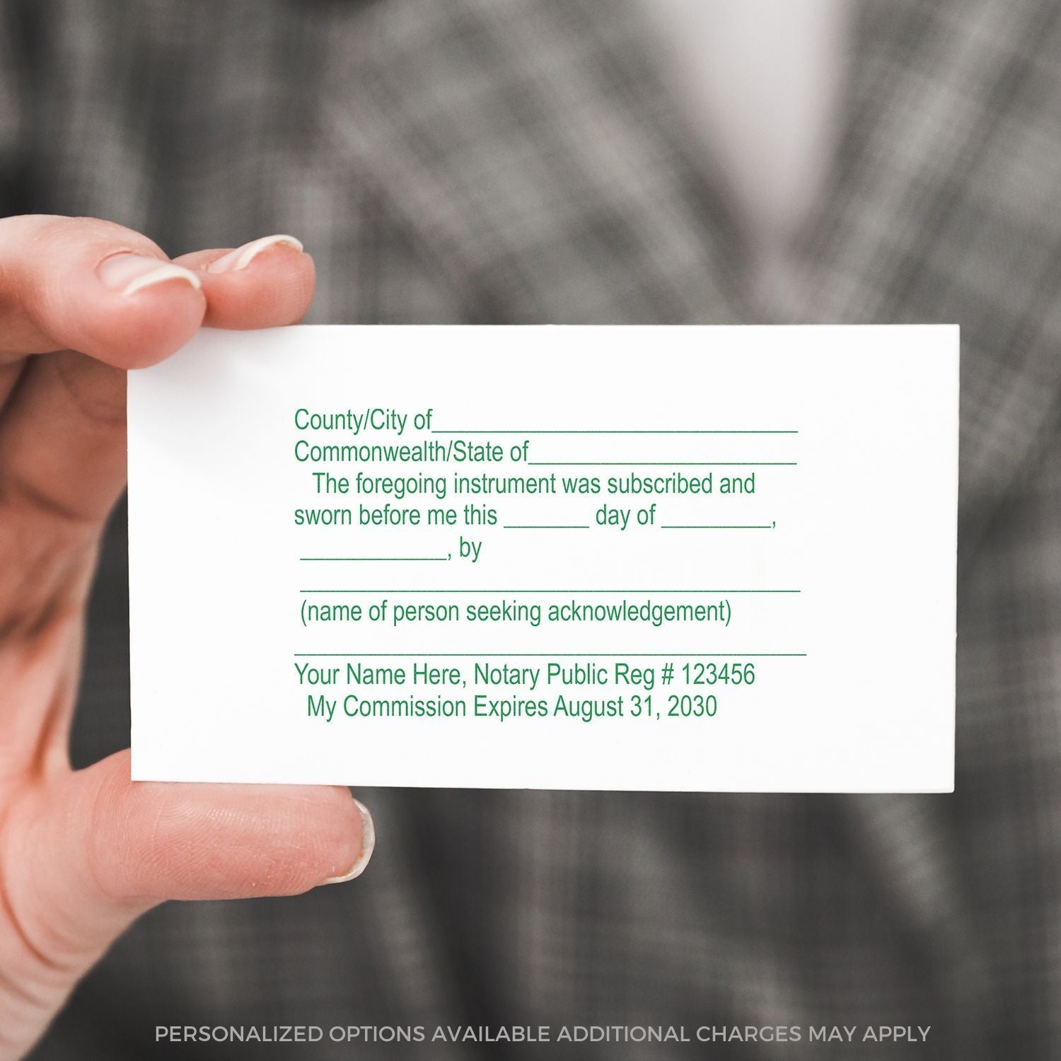 A hand holding a card with a Self Inking Notary Jurat Stamp imprint, showing fields for county, date, name, and notary details in green text.