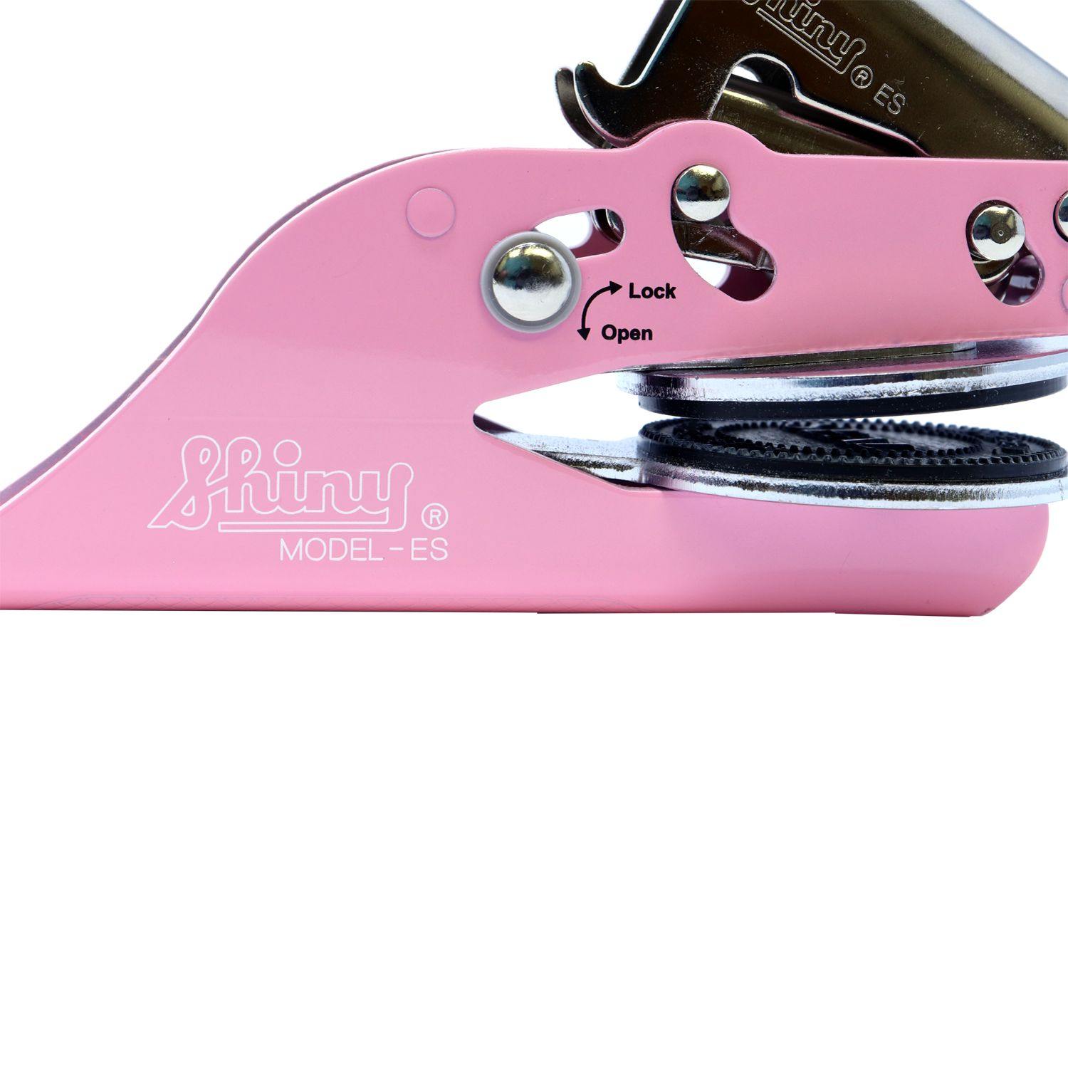 Close-up of the Architect Pink Seal Handheld Embosser in an unlocked position, showing the shiny metal embossing plates and the lock mechanism on the pink body.