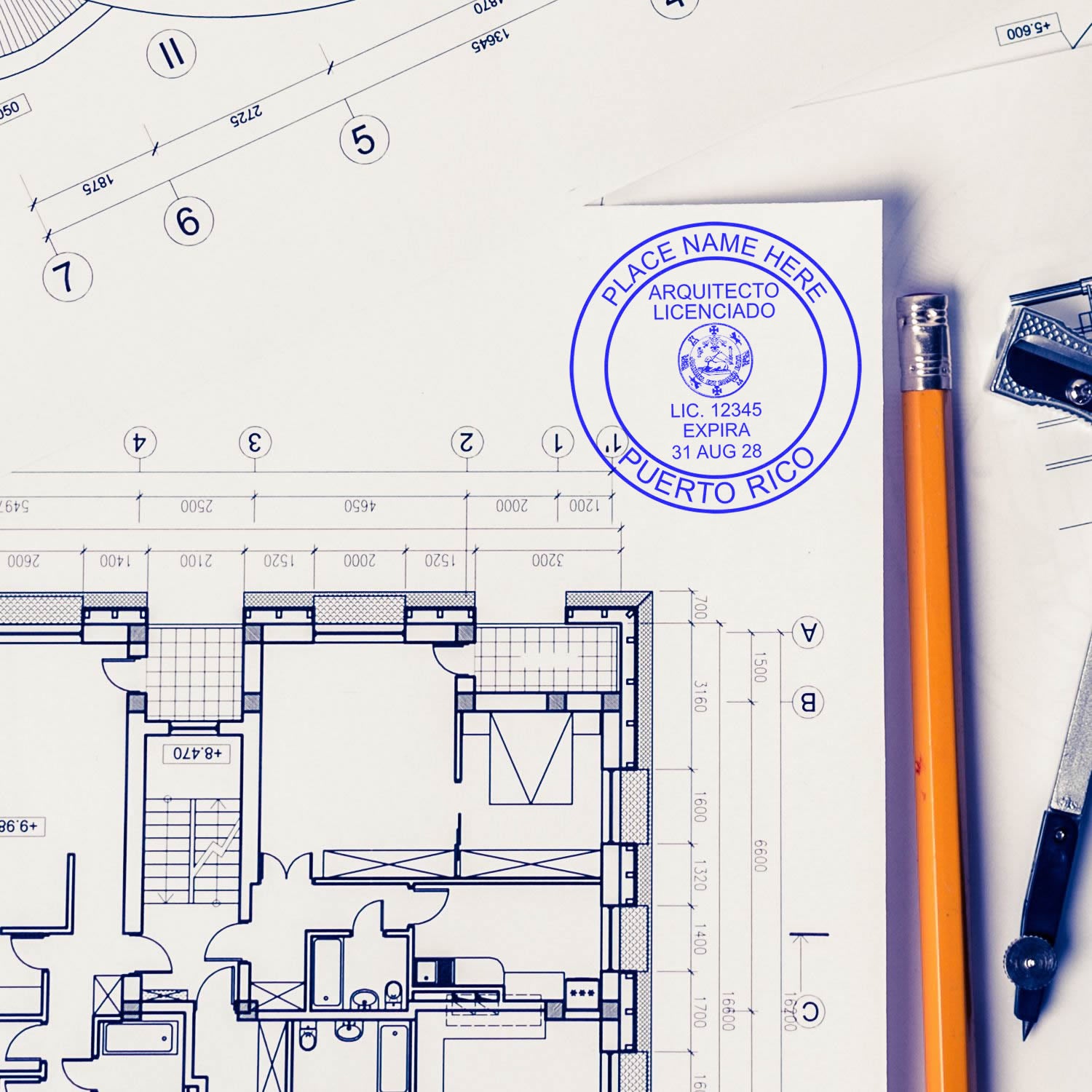 Self Inking Puerto Rico Architect Stamp in use on architectural blueprints with a pencil and drafting tools nearby.