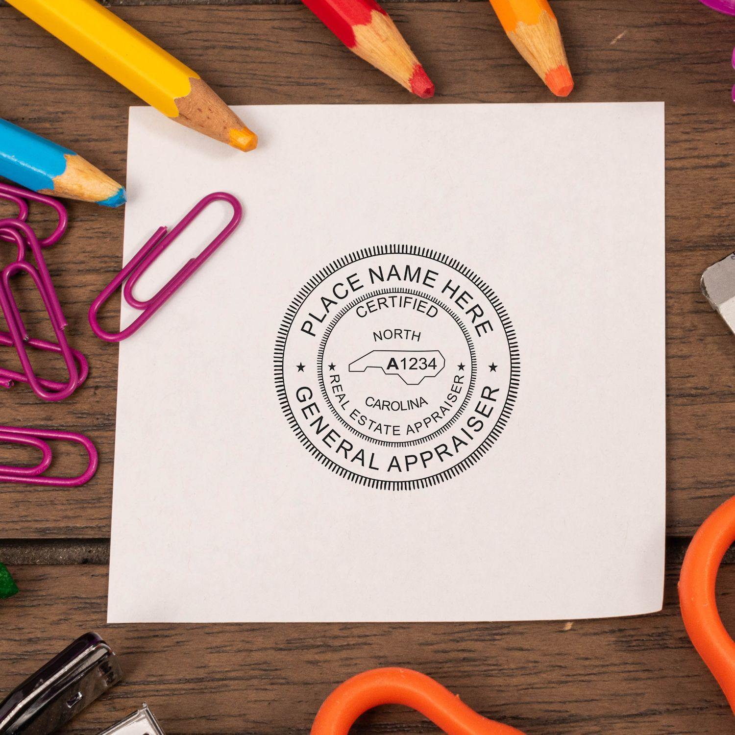 Real Estate Appraiser MaxLight Pre Inked Rubber Stamp of Seal in use on a white paper surrounded by colorful office supplies.