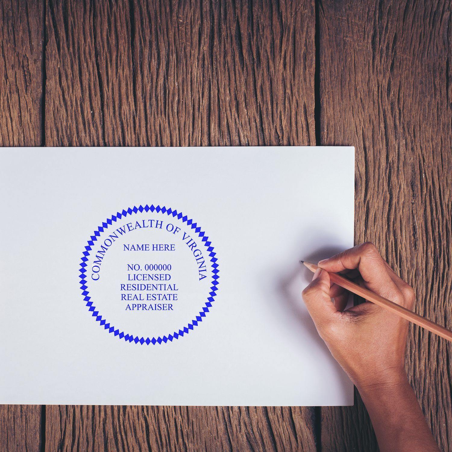 Hand using the Real Estate Appraiser Self Inking Rubber Stamp of Seal on a document, displaying a blue seal with text on a wooden surface.