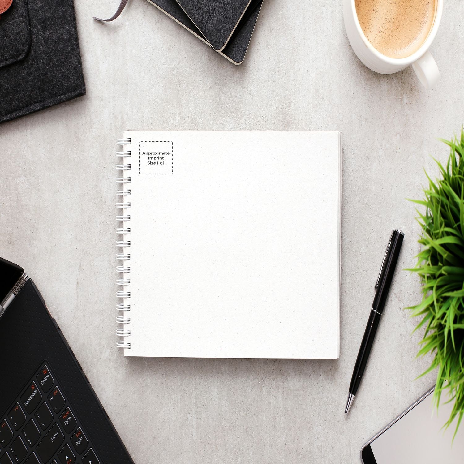 Custom Rubber Stamp Size 1 x 1 on a white notebook, surrounded by a pen, laptop, coffee cup, and plant on a gray desk.