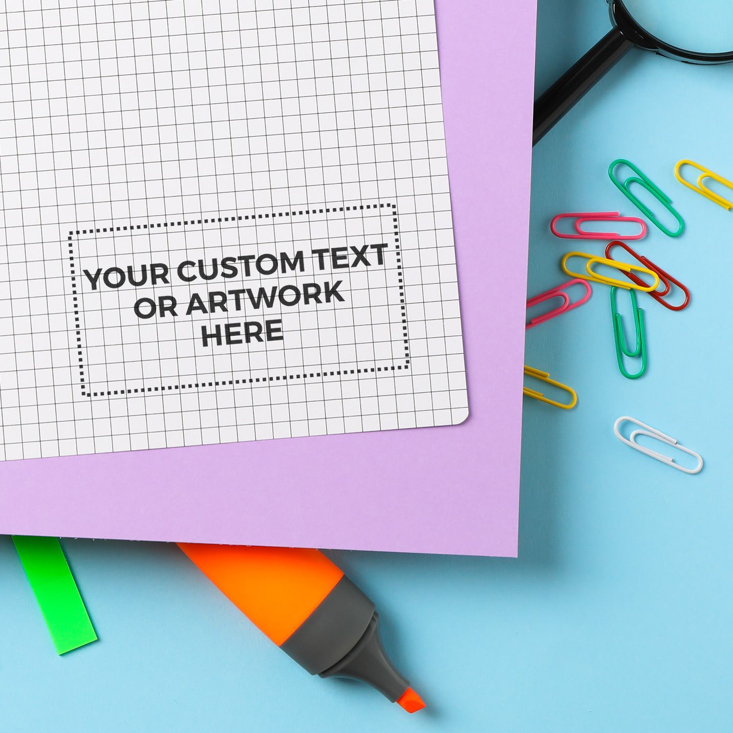 Custom Rubber Stamp Size 1 x 2 stamped on graph paper, surrounded by colorful paper clips, a magnifying glass, and a highlighter.