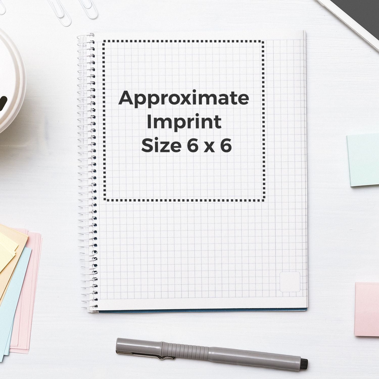 Custom Rubber Stamp Size 6 x 6 shown on a spiral notebook with grid paper, surrounded by a pen, sticky notes, and paper clips.