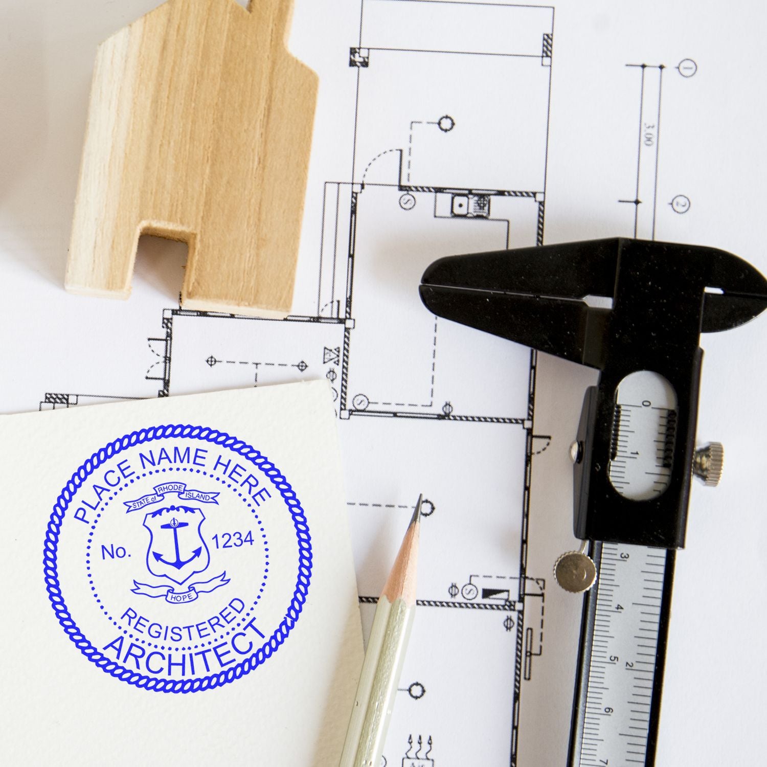 Self Inking Rhode Island Architect Stamp in blue ink on paper, next to architectural plans, a pencil, a caliper, and a wooden house model.