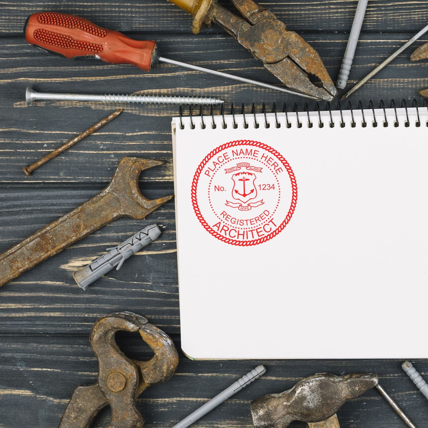 Premium MaxLight Pre-Inked Rhode Island Architectural Stamp on a notebook, surrounded by various rusty tools on a wooden surface.