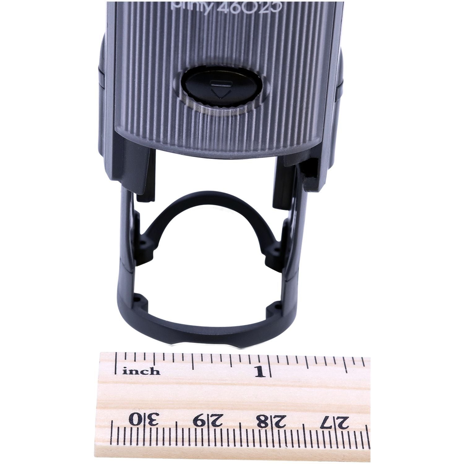 Self Inking Round COD Stamp with a black handle and a wooden ruler showing measurements in inches placed in front of it.