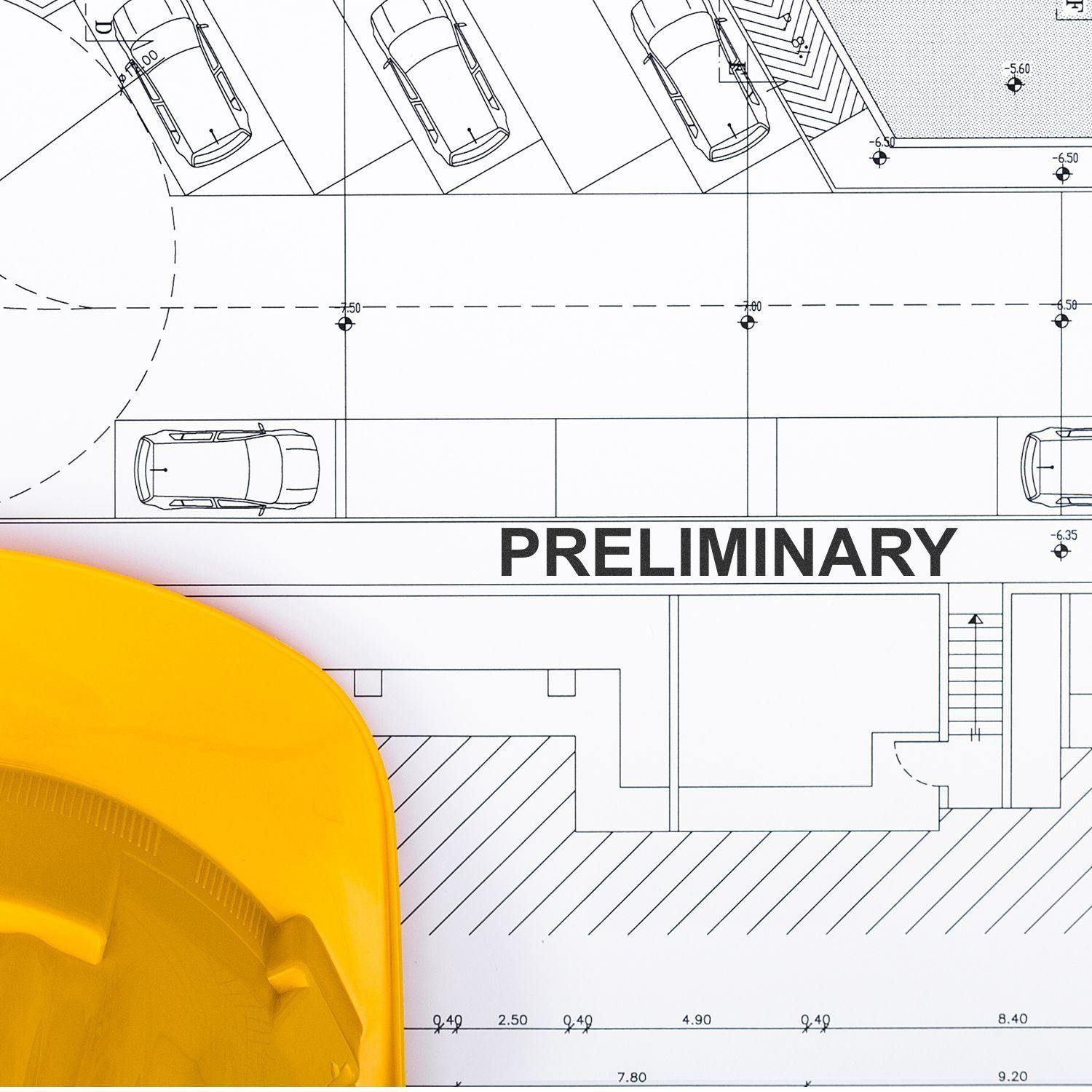 Self Inking Preliminary Stamp marking a blueprint with PRELIMINARY text, next to a yellow hard hat.