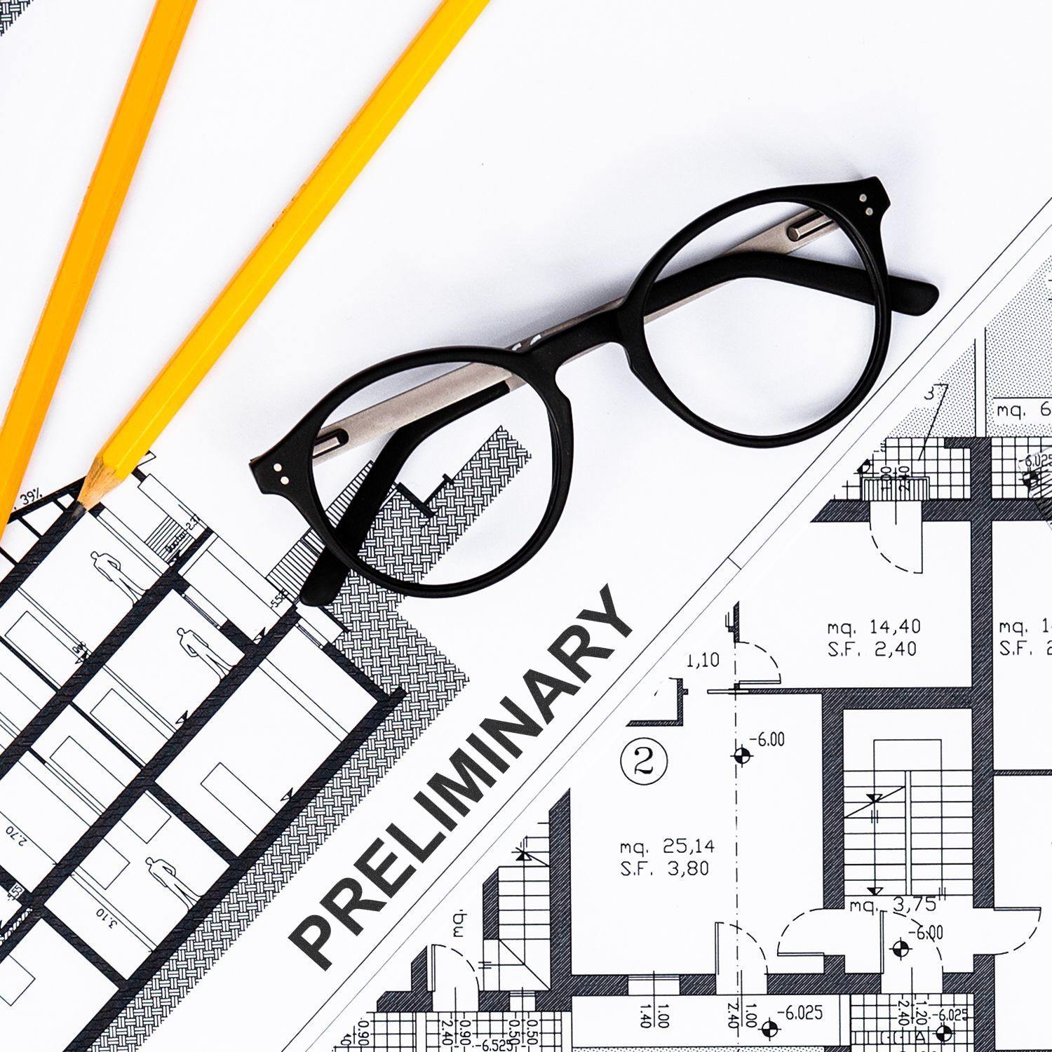 Self Inking Preliminary Stamp on architectural plans with black glasses and yellow pencils nearby.