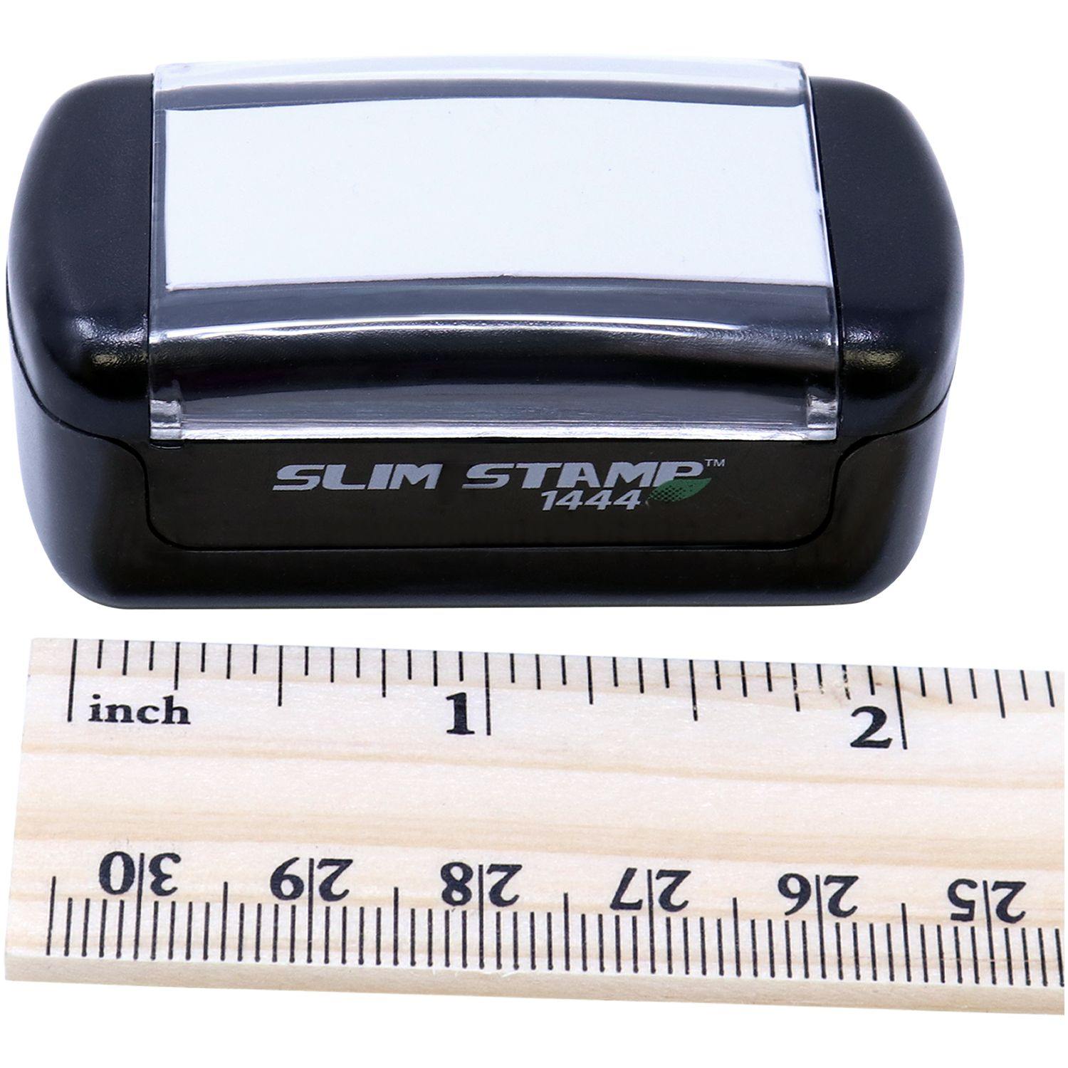 Slim Pre-Inked Fax Stamp 1444 next to a wooden ruler showing measurements in inches and centimeters.