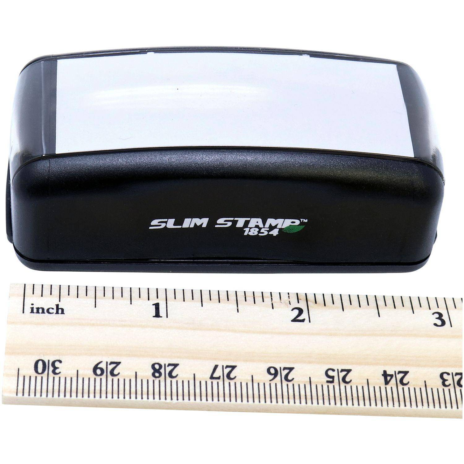 Large Pre-Inked Good Work Stamp, black with a white top, next to a wooden ruler showing its compact size.