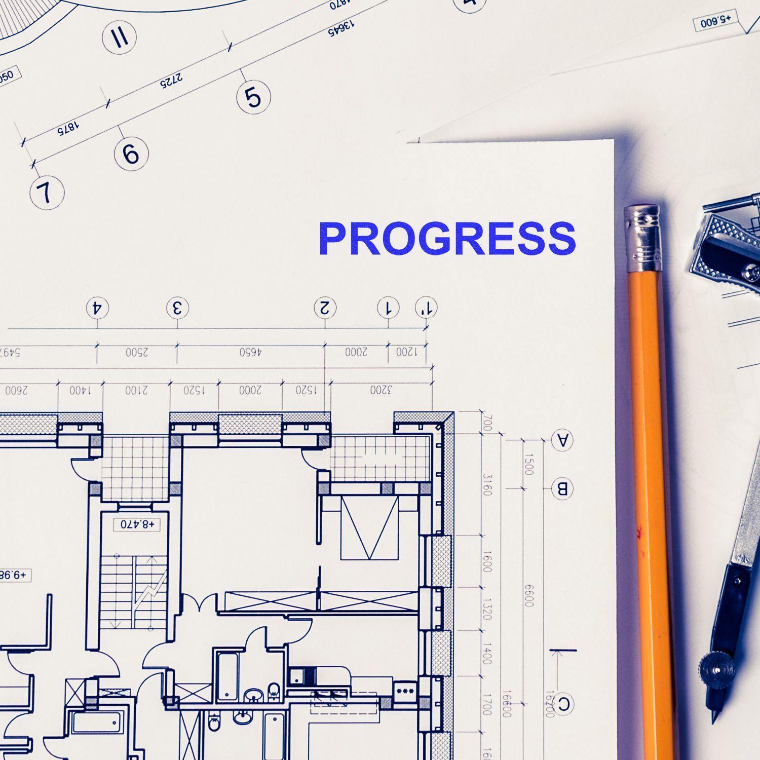 Slim Pre-Inked Progress Stamp marking 'PROGRESS' on architectural blueprints with a pencil and drafting tools nearby.