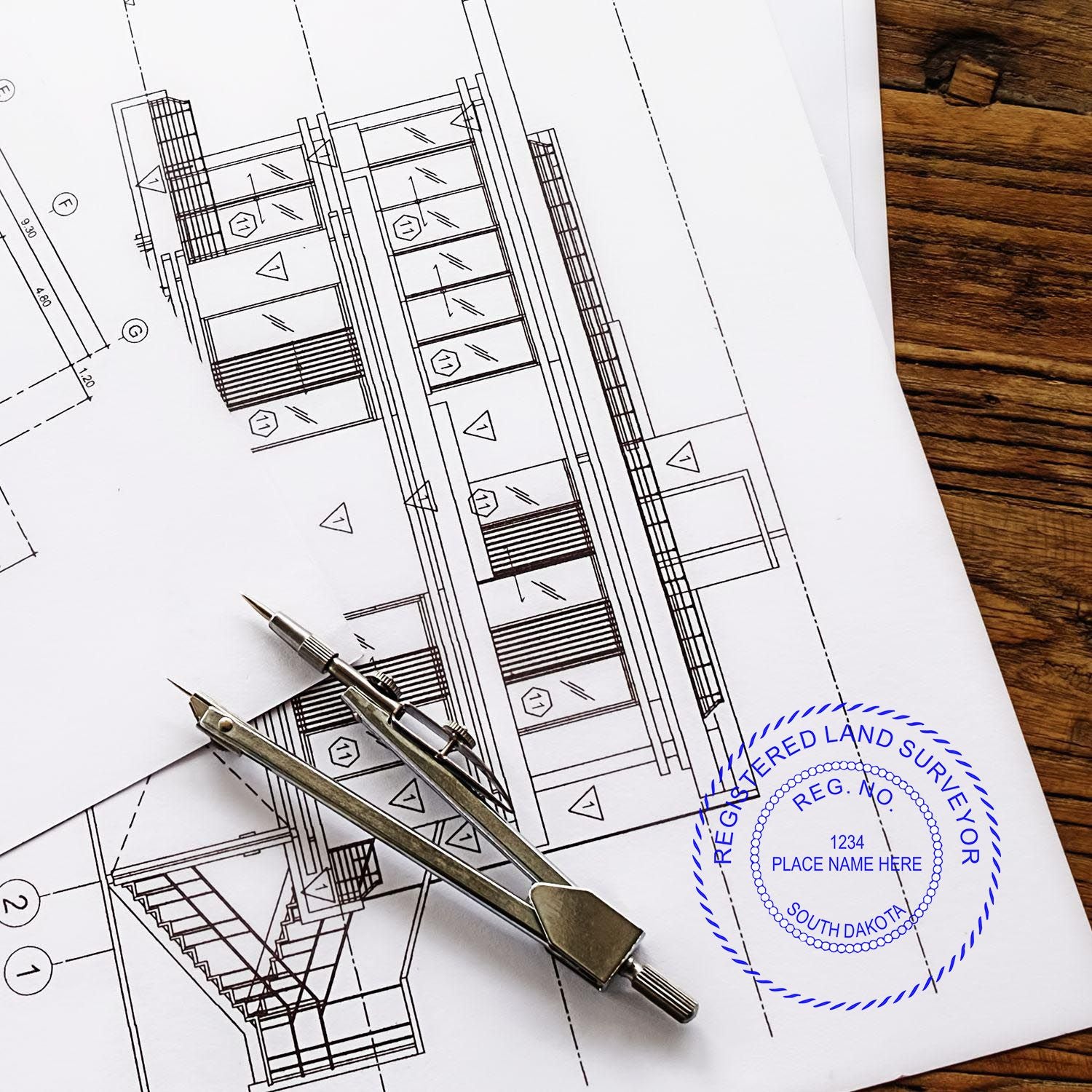 Premium MaxLight Pre-Inked South Dakota Surveyors Stamp used on architectural plans with a compass on a wooden table.