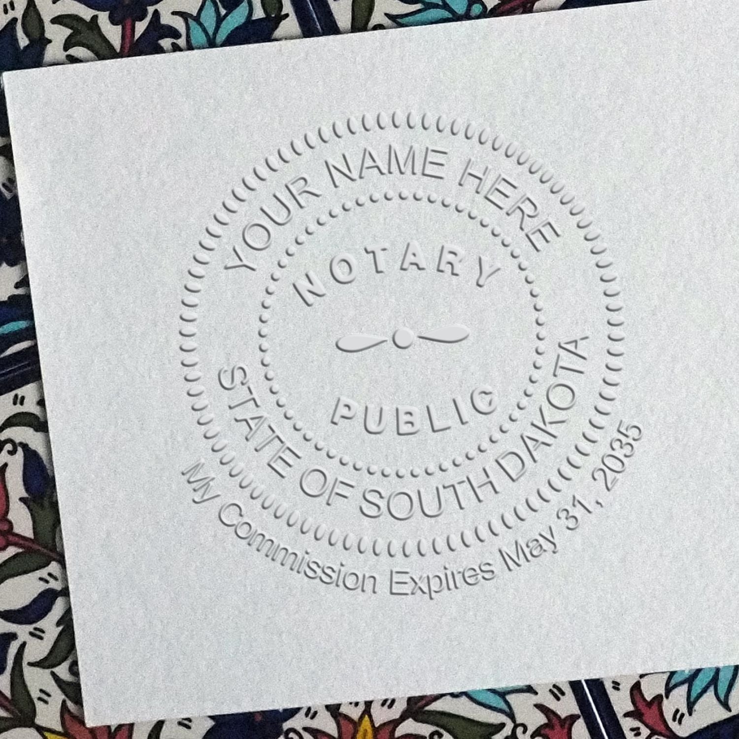 A lifestyle photo showing a stamped image of the South Dakota Handheld Notary Seal Embosser on a piece of paper