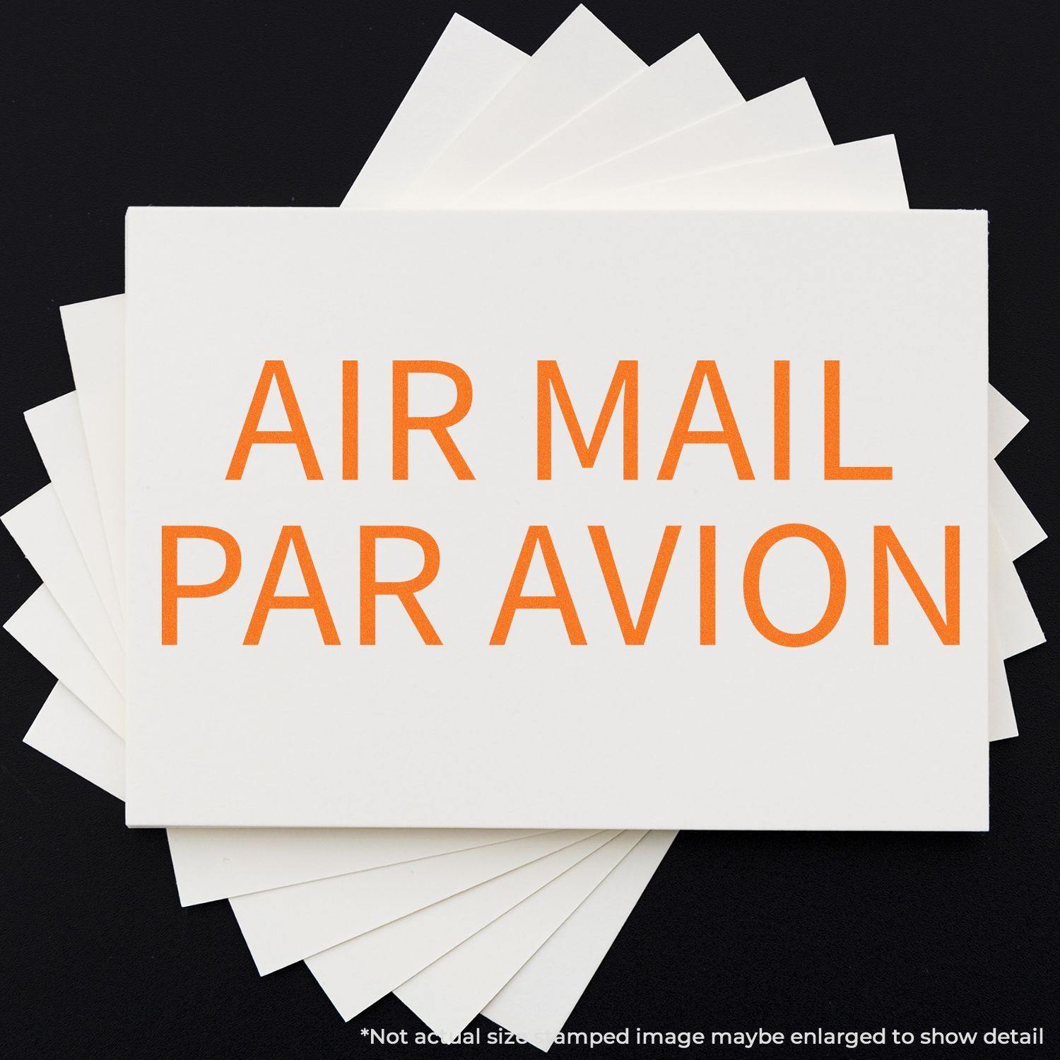 Air Mail Par Avion rubber stamp impression in bold orange letters on a white card, displayed on a black background.