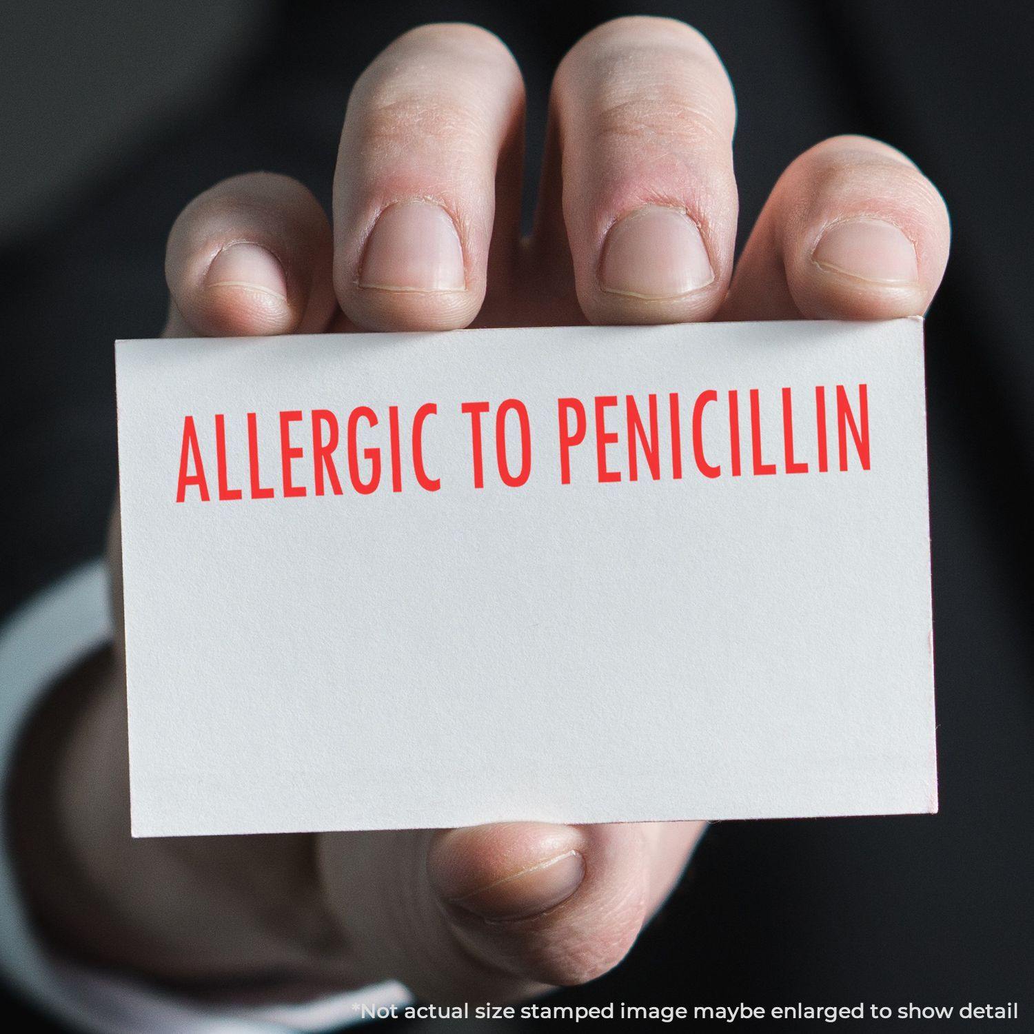 A hand holding a card with ALLERGIC TO PENICILLIN stamped in red, indicating an allergic reaction to penicillin.