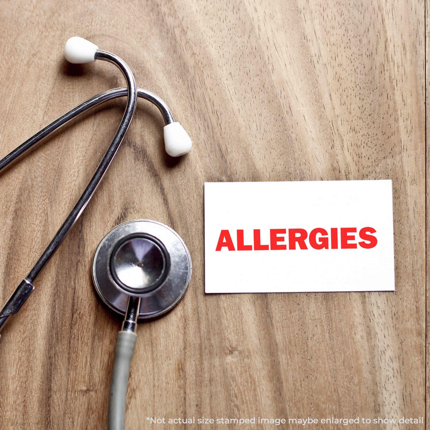 A stethoscope on a wooden surface next to a card stamped with "ALLERGIES" in red using the Allergies Rubber Stamp.