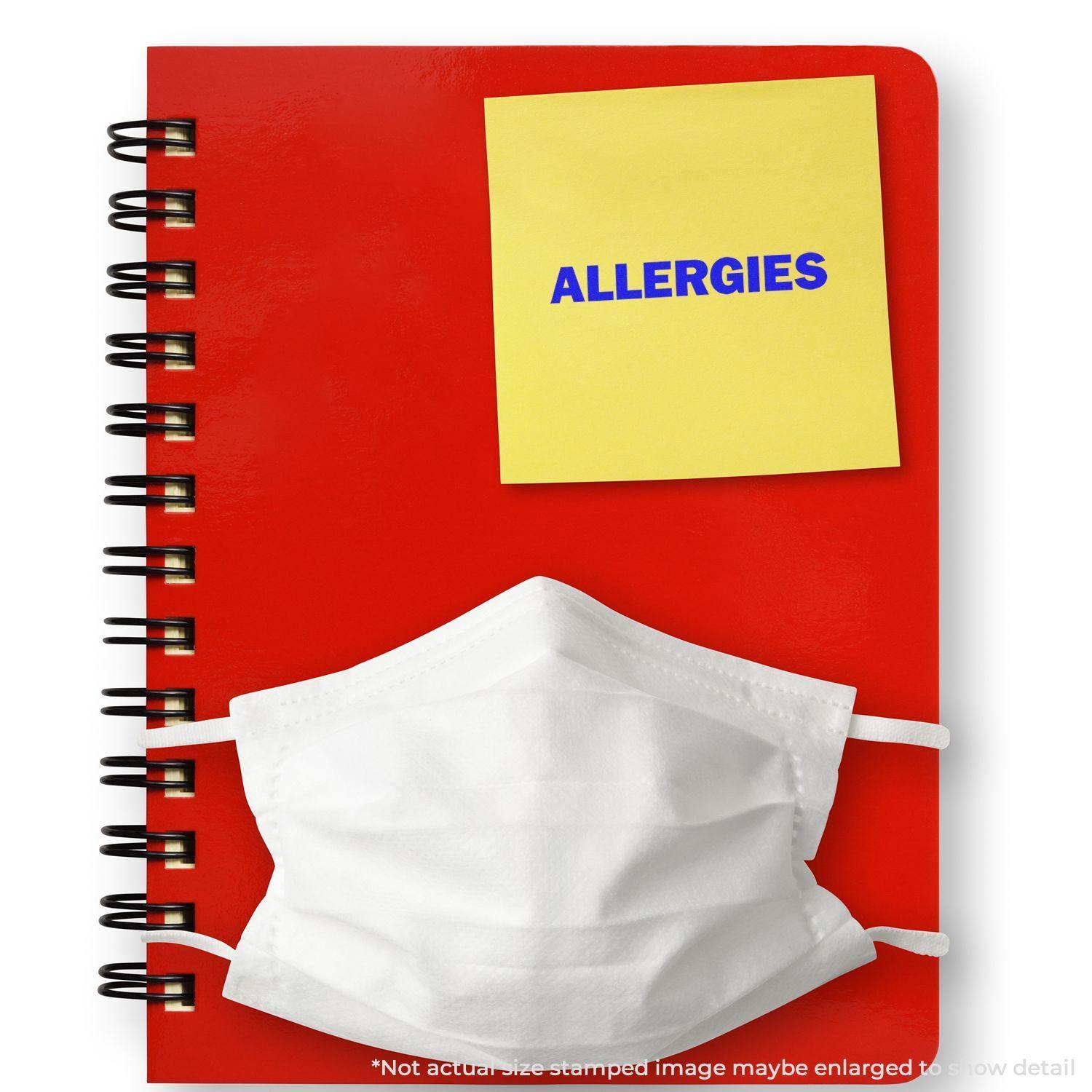 Allergies Rubber Stamp on a yellow sticky note attached to a red spiral notebook with a white face mask placed on top.